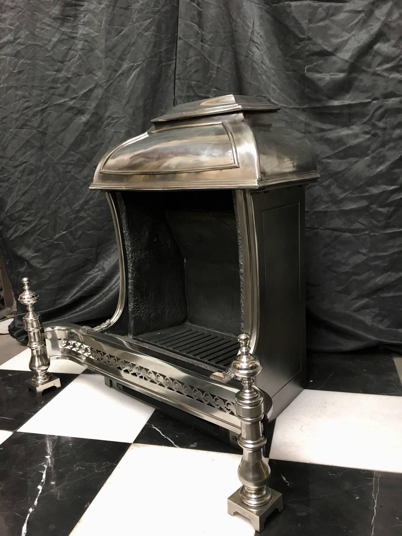 A late 19th century cast Iron hooded fire grate, possibly Paktong in the Beaux-Arts style. A shaped hood sits above a pair of sweeping gables, at the base of each gable are a pair of stylised Acanthus leaves, with a cut apron mounted with a pair of