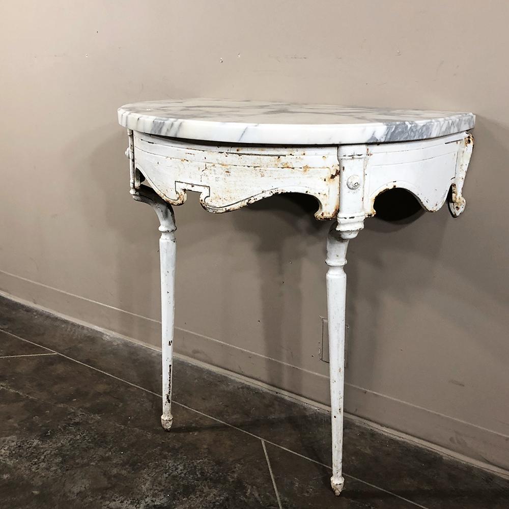 19th century cast iron demilune marble top console represents an unusual find, originally used in conservatory or garden with the framework consisting of intricately detailed cast iron supported by two legs, which requires mounting to the wall. A