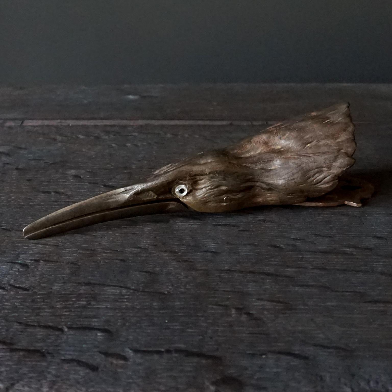 Seltene schwere französische Gusseisenklammer aus dem 19. Jahrhundert mit Feder in Form eines Vogelkopfes. 
Wahrscheinlich handelt es sich um einen Reiher, dessen Schnabel durch das Scharnier in seinem 