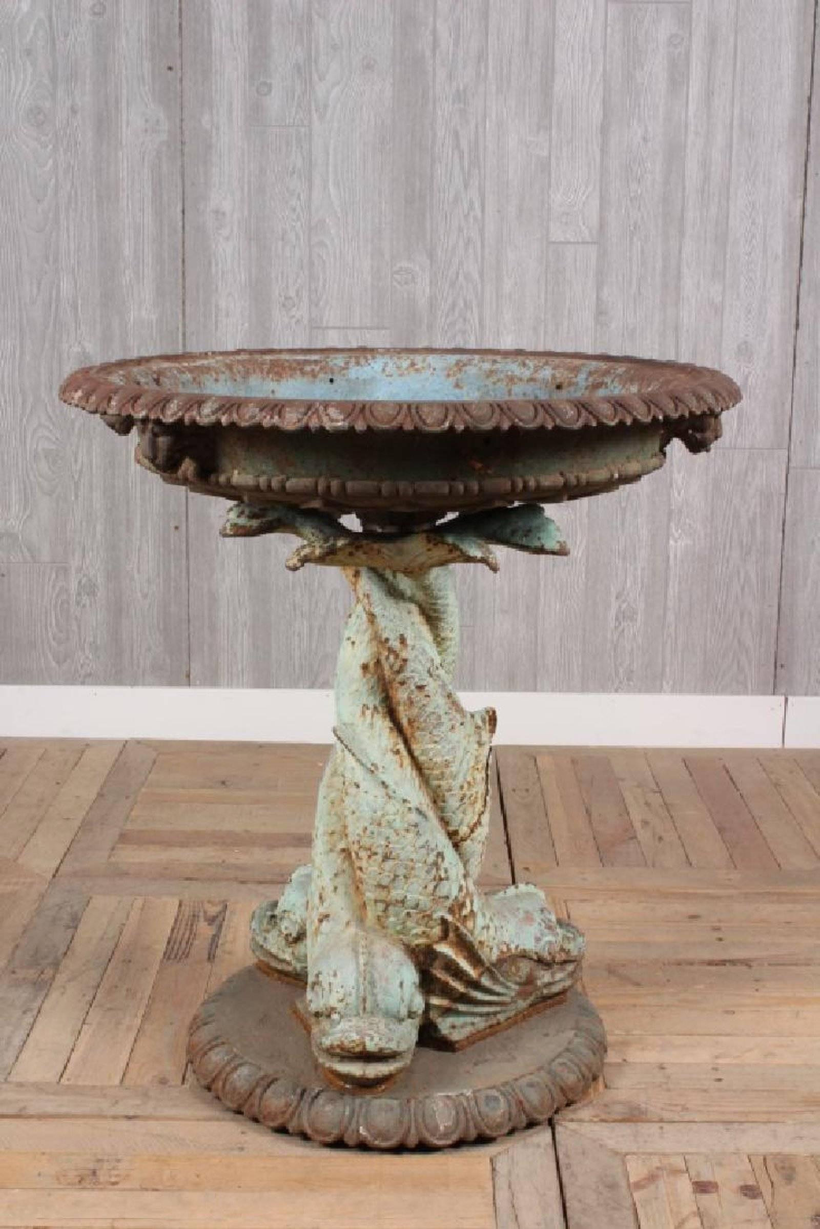 Late 19th century Cast Iron Fountain has shallow bowl with egg and dart rim. Lion Heads surround the bowl that sits atop a pair of twisted dolphins with superb blue green paint. Scales of the dolphins are especially nice as is all the other details.
