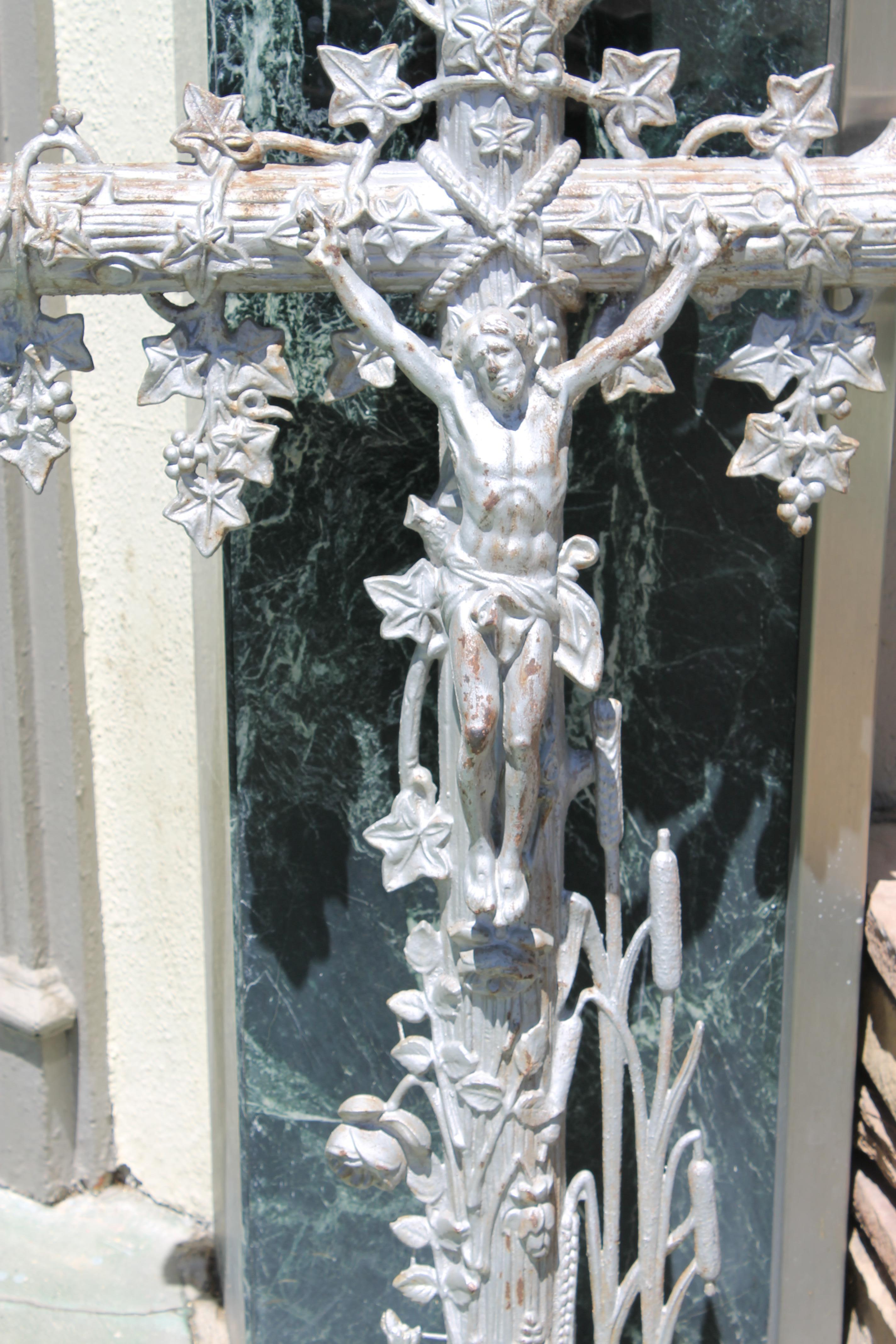 A circa 1880s crucifix grave marker, heavy cast iron with original silver paint. Cross is covered in vines and leaves with cat tails and grasses at the base. These raised decorations wrap all the way around the back as well. Crucifix measures 26