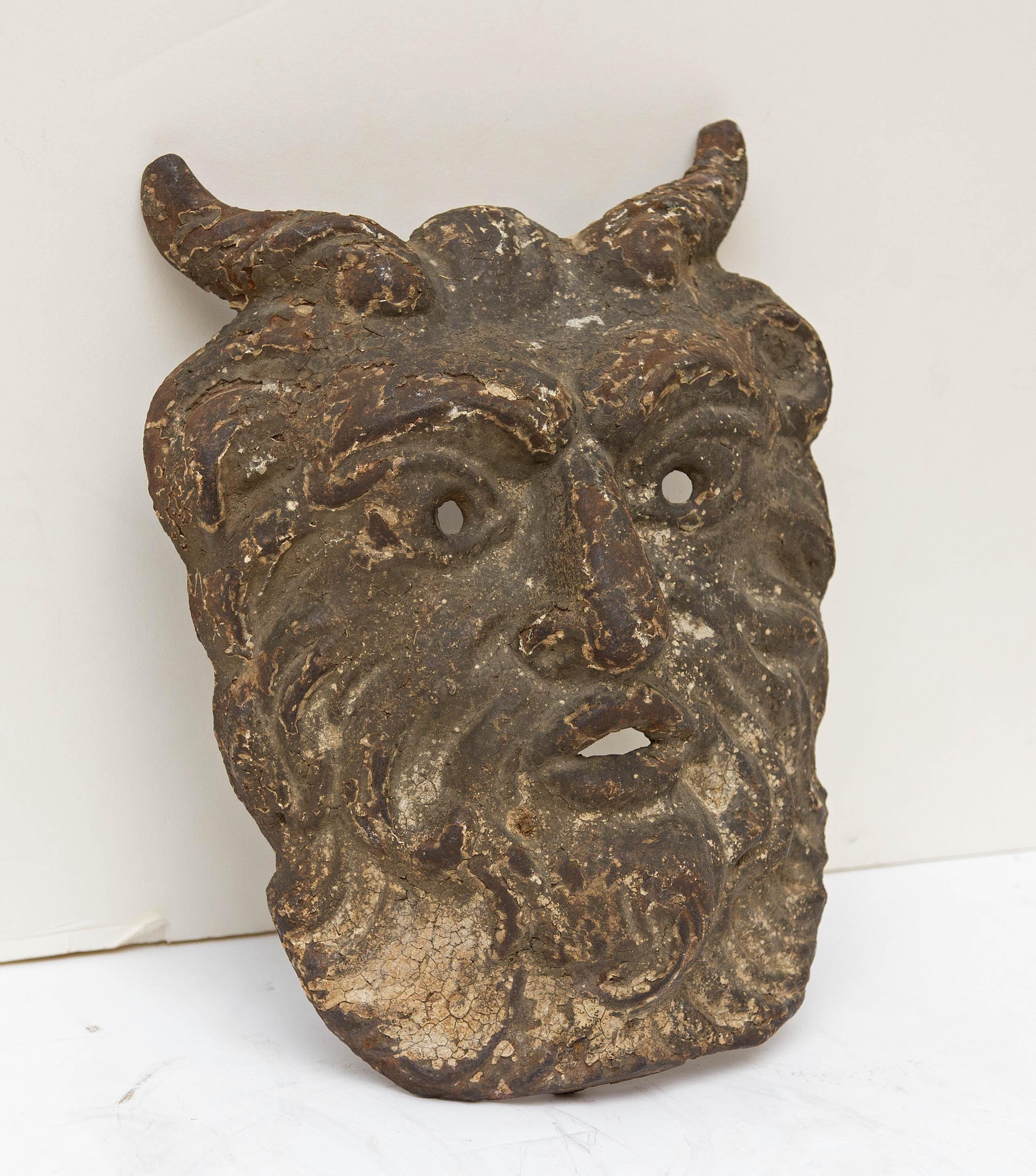 Antique cast iron mask of satyr. An architectural element.