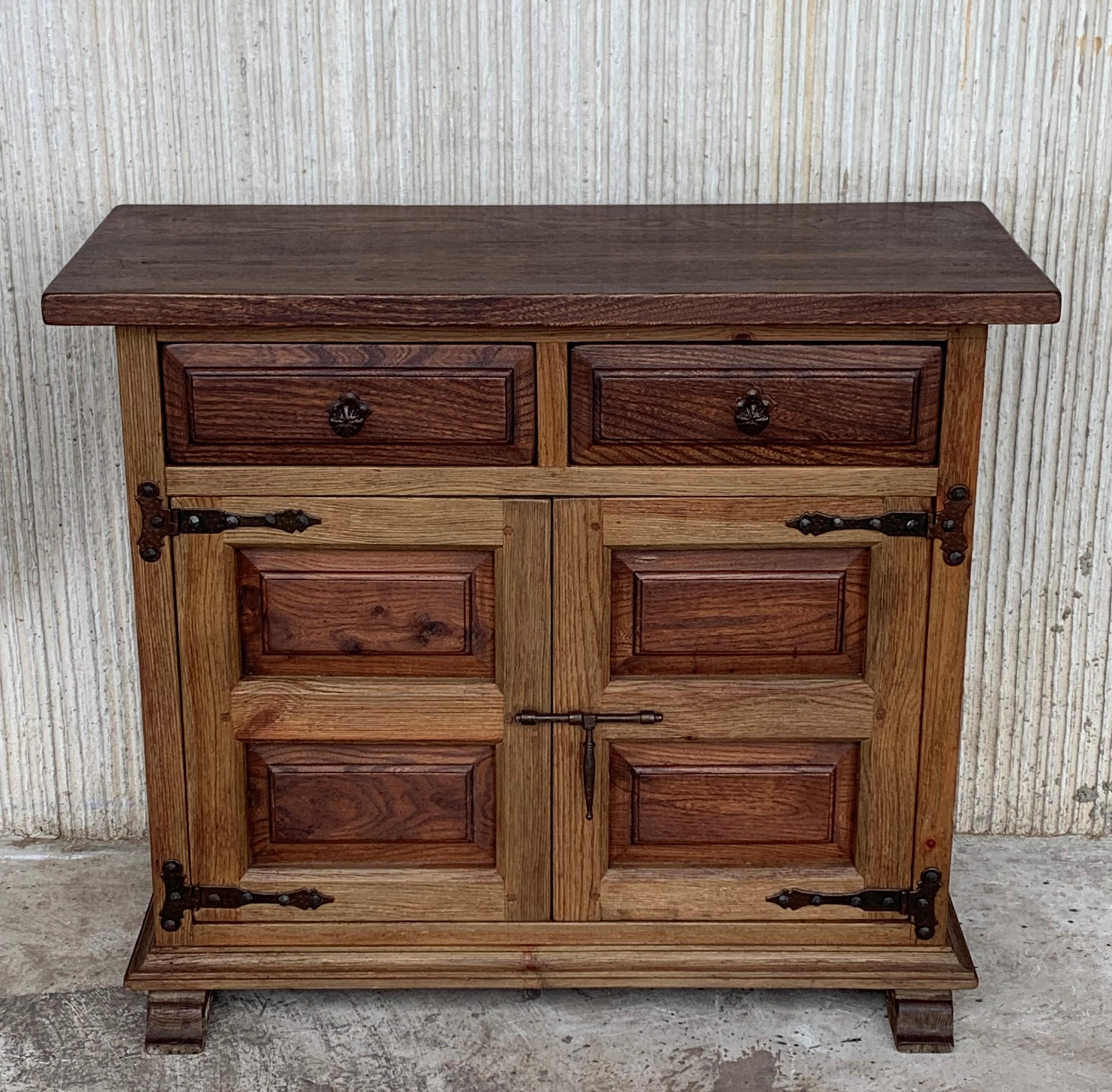 Proveniente dalla Spagna settentrionale, costruito in legno massiccio di quercia, il piano rettangolare con bordo sagomato è costituito da una cassa conforme che ospita due cassetti su due ante, le ante sono rivestite in noce massiccio e poggiano su