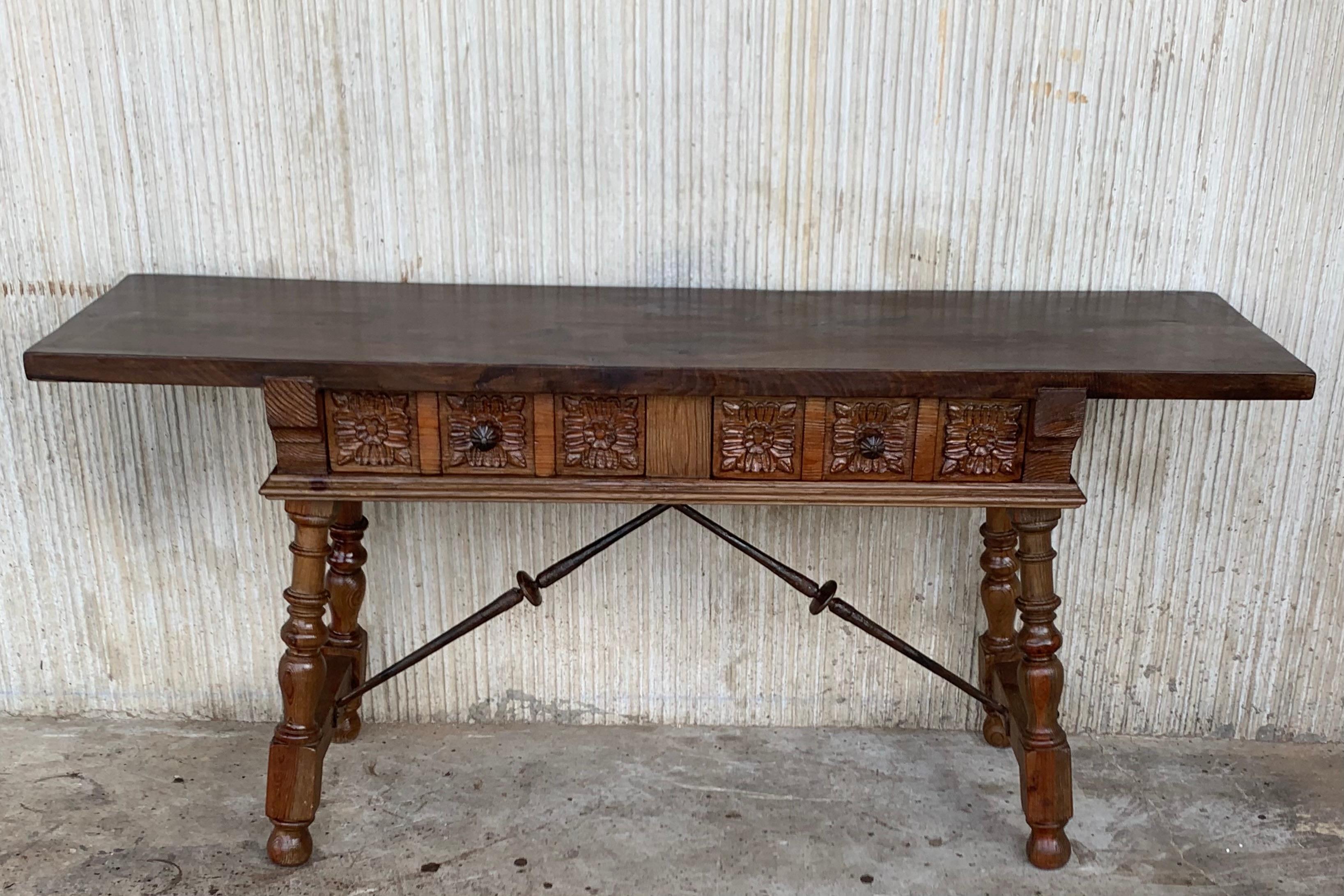 A Spanish Baroque style walnut table from the late 19th century, with two drawers, caved legs and iron hardware. Born in Spain in the first decade of the 20th century, this exquisite walnut table features a rectangular planked top sitting above two