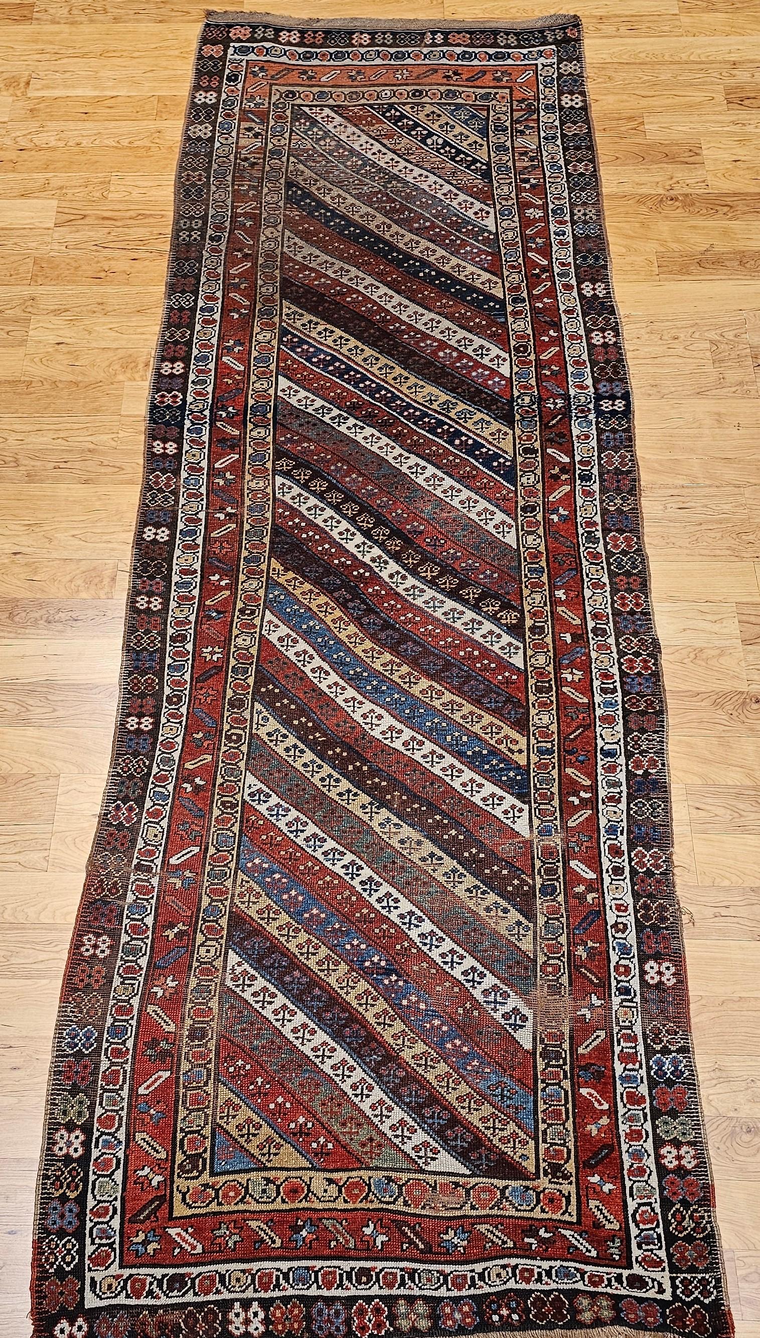 Beautiful and very colorful Caucasian Gendje Kazak runner from the late 1800s.   The Gendje runner is in an allover skewed stripe pattern with an alternating ivory, green, wheat, brown, French blue and red each containing a small flower head design.