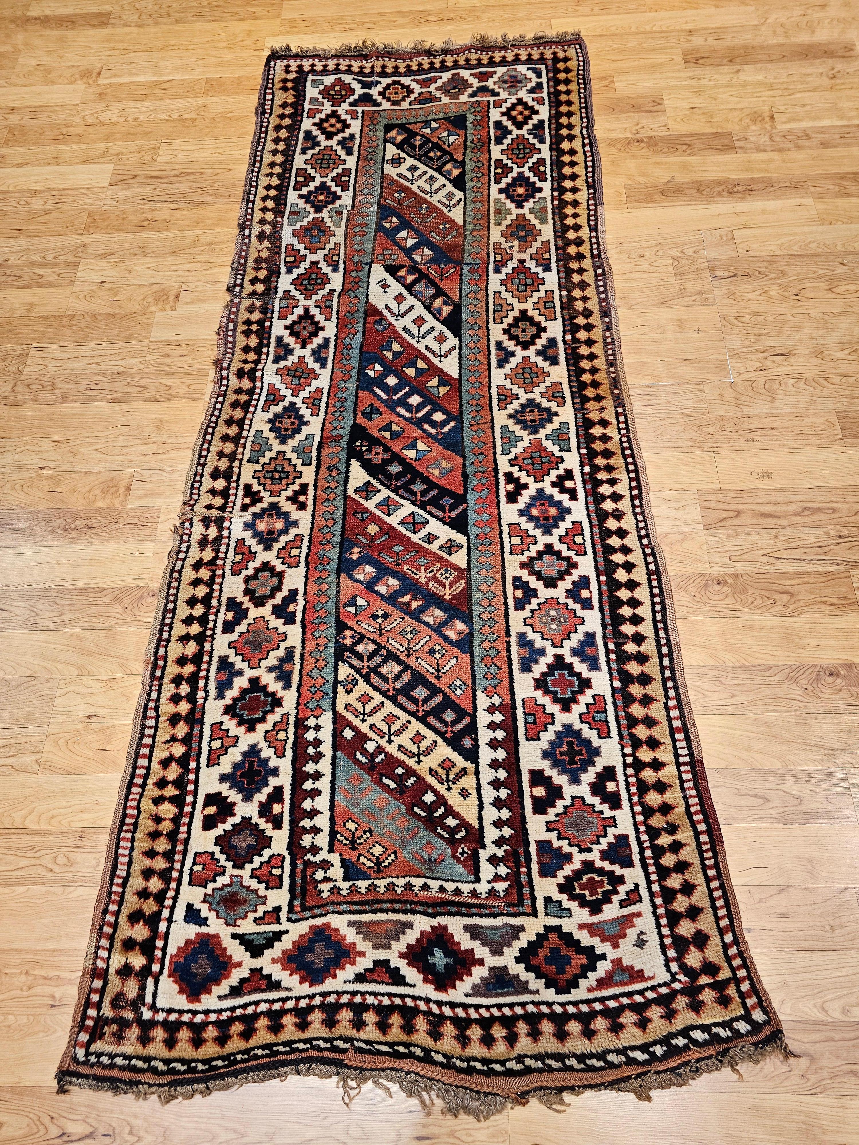 Beautiful and colorful vintage Caucasian Gendje Kazak runner from the late 1800s.   The Gendje runner is in an allover skewed stripe pattern with an alternating navy and ivory background with small geometric design.  The border is in ivory with star