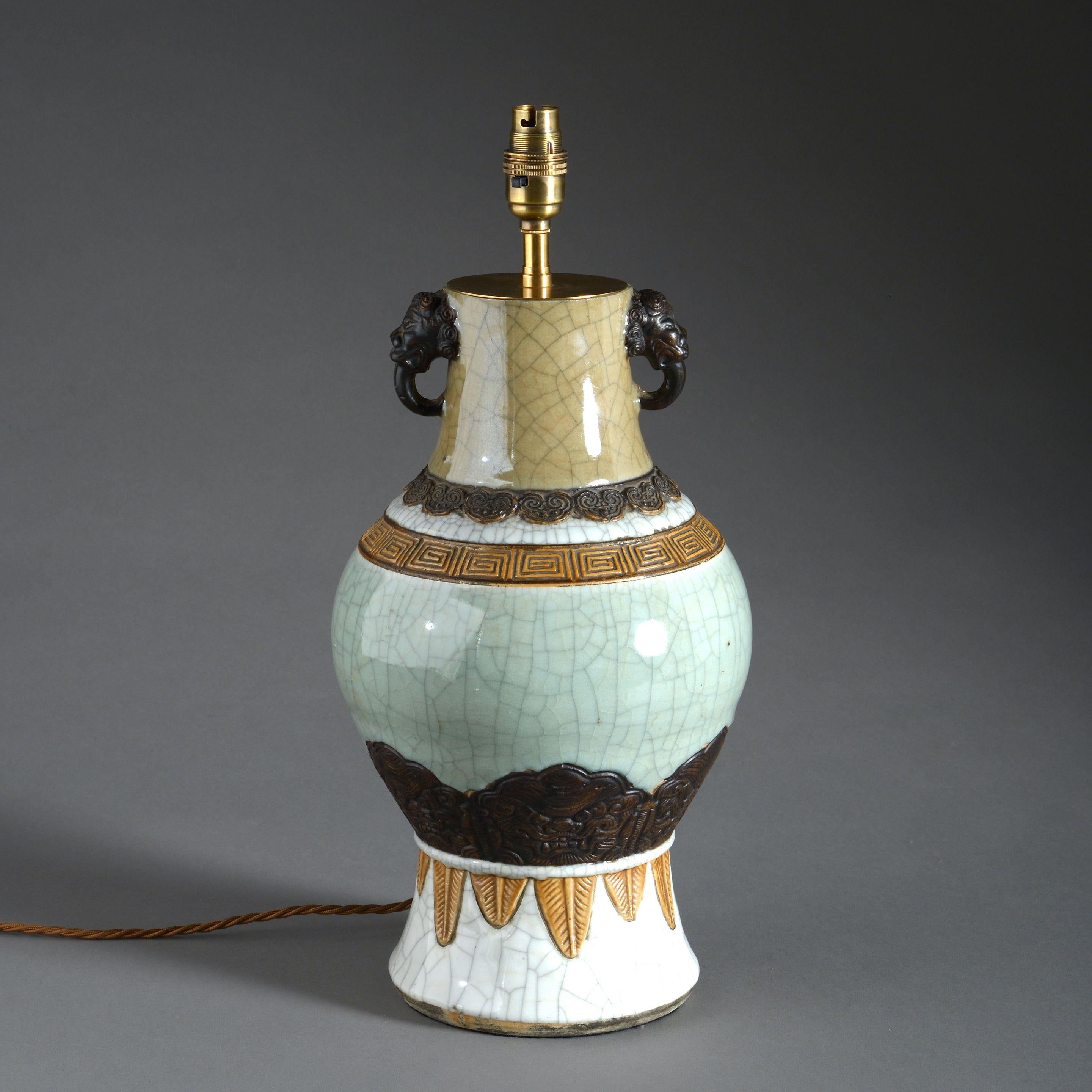A mid-19th century vase of good scale, the body of celadon, caramel and white crackle glazes, having bronzed elephant head handles about the neck. 

Qing Dynasty.