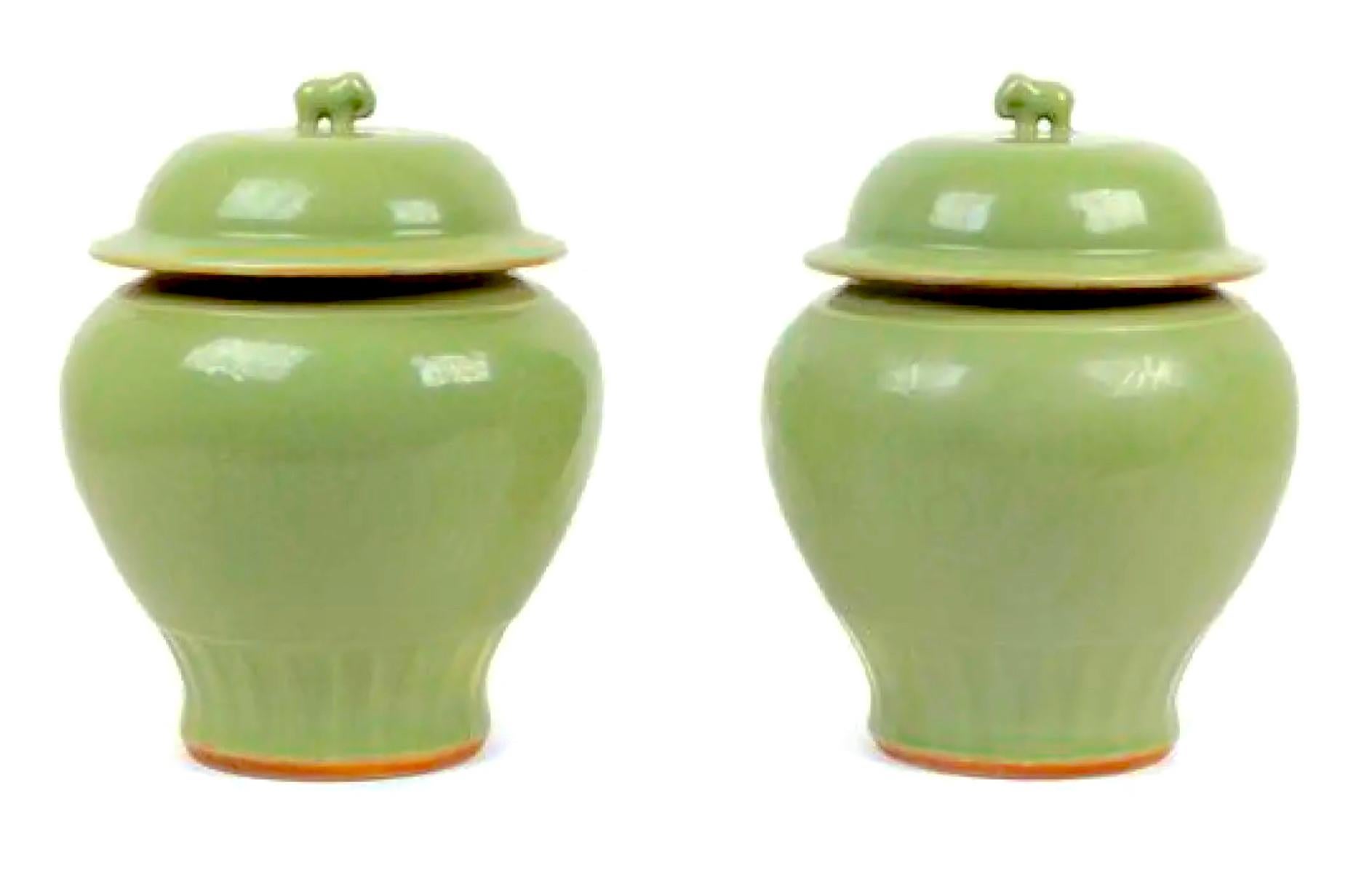 A standout pair of late 19th-century Chinese authentic celadon, heavy, artisan-made ginger jars with elephant finials, both lids intact, making for the perfect duet.