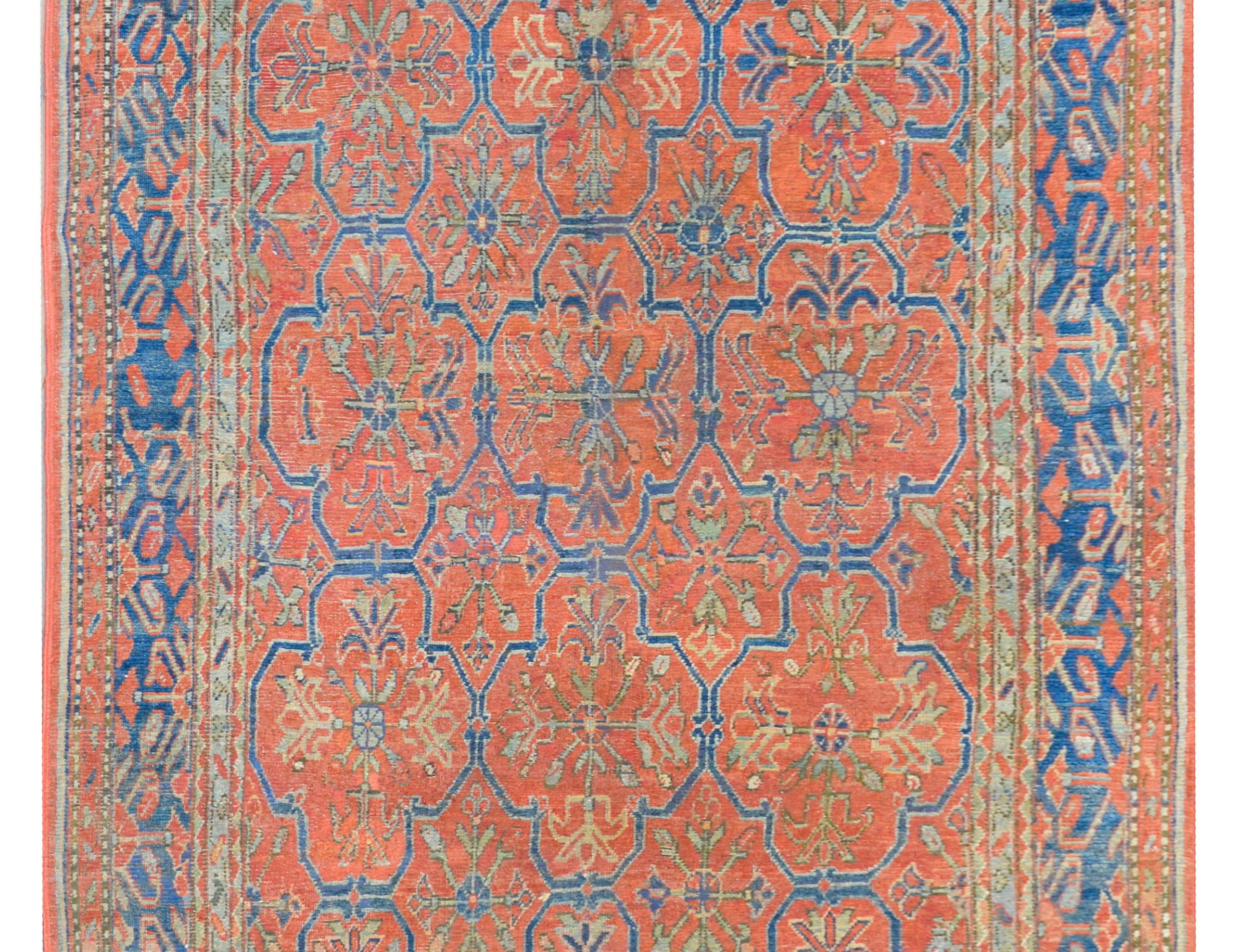 Rare et inhabituel tapis d'Asie centrale du XIXe siècle, présentant un fantastique motif floral en treillis tissé en indigo clair et foncé, jaune et vert, sur un fond cramoisi, et entouré d'une étonnante bordure composée de multiples petites et