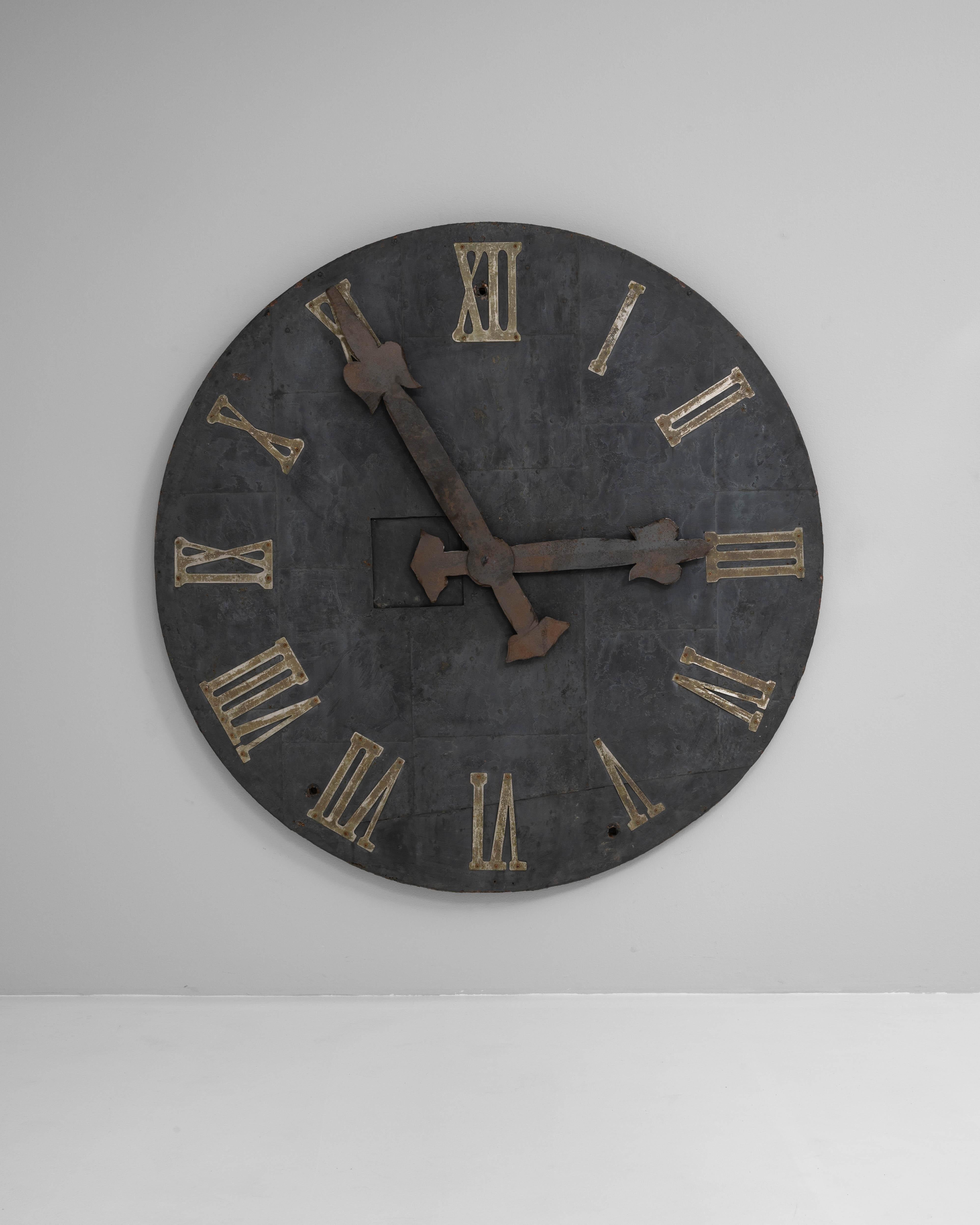 Questo straordinario orologio da parete industriale del XIX secolo proviene dall'Europa centrale ed è realizzato in metallo invecchiato con una patina che racconta la storia del tempo. La forma circolare di grandi dimensioni presenta numeri romani