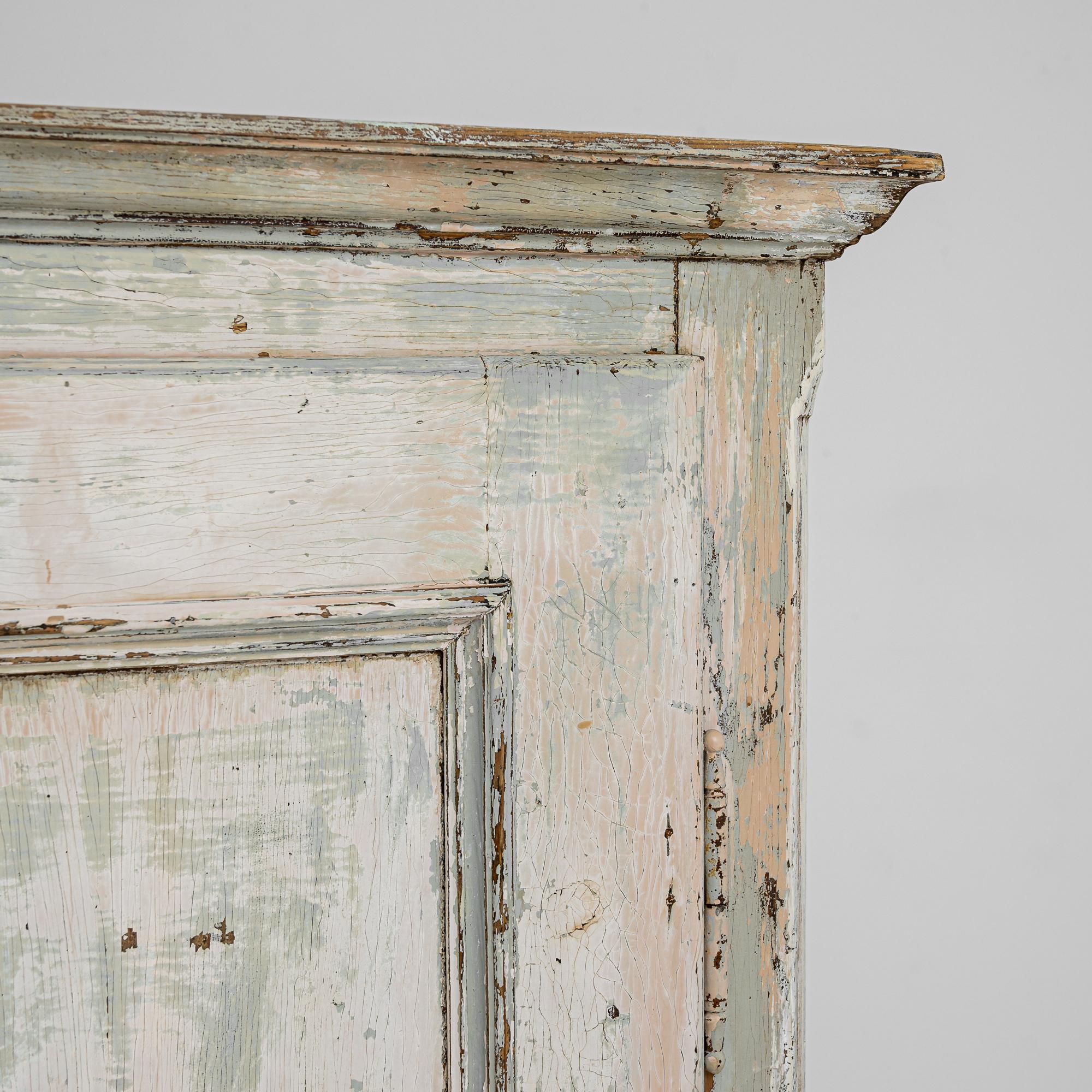 Ce meuble en bois ancien associe une silhouette champêtre simple à une palette de couleurs douces pour un résultat charmant. Fabriquée en Europe centrale au XIXe siècle, une grille métallique circulaire au centre de la porte de l'armoire indique que