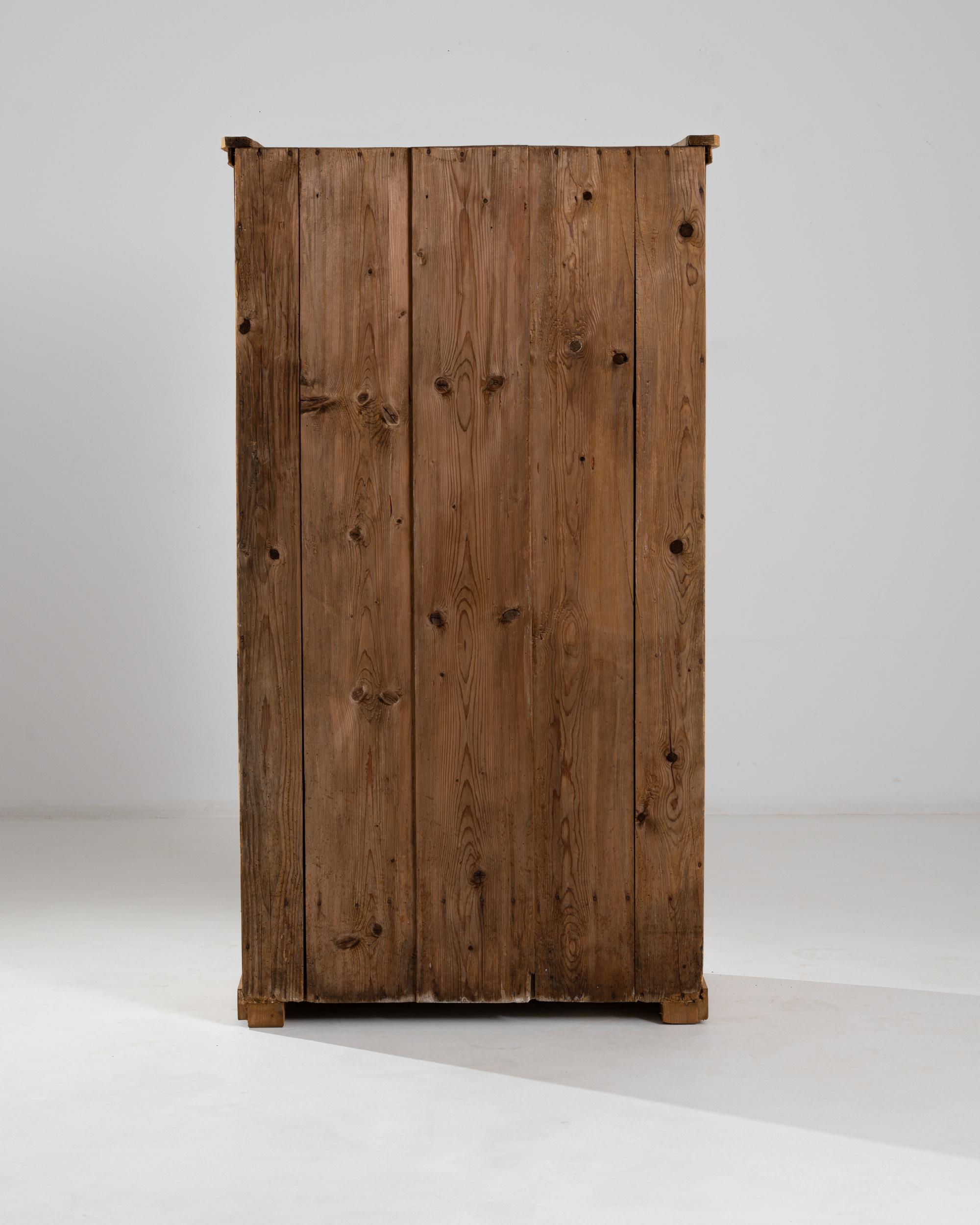 Experience the timeless elegance of this 19th-century Central European wooden cabinet, showcasing a natural wood finish that exudes warmth and authenticity. A single door, beautifully crafted and adorned, opens to unveil a spacious interior with two