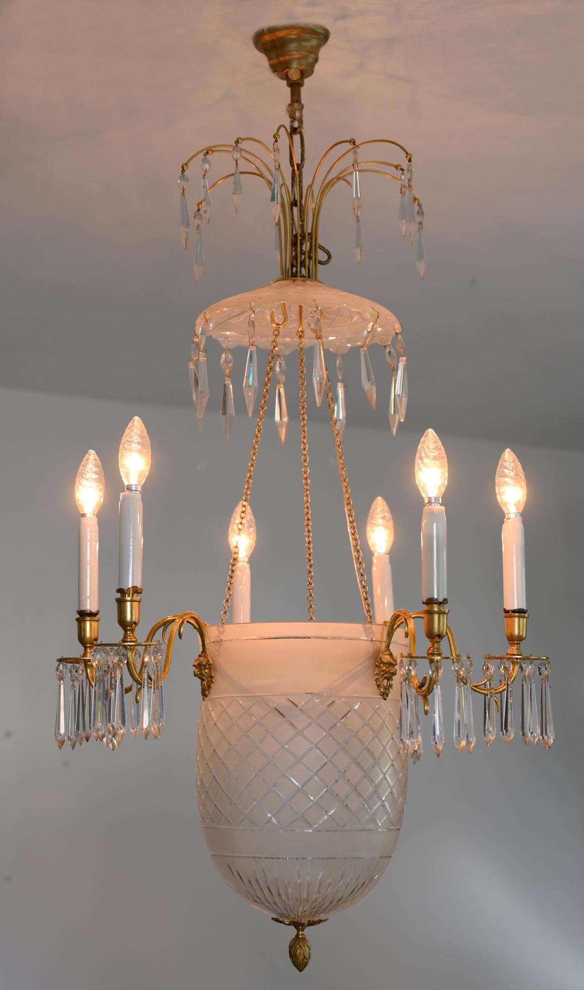 The chandelier is probably made circa 1810 in Sweden or the Baltic States. It is made out of cut glass and flashed glass the three double arms and the mascarons are gilded.