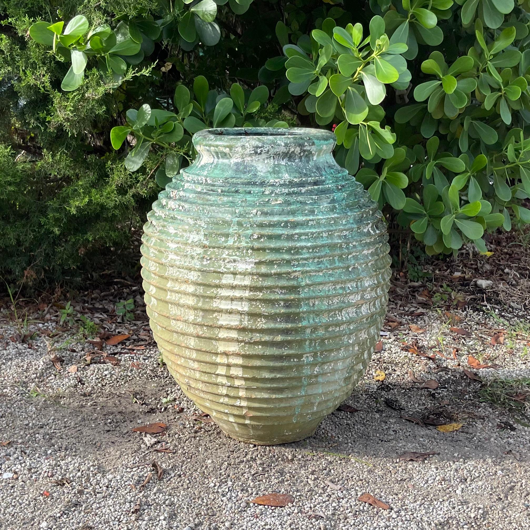 Vaso per olive del Peloponneso greco del XIX secolo con la tipica decorazione a coste Nekuma sul corpetto rotondo in terracotta. La superficie irregolare presenta i resti originali del colore verde storico.  Lievi sbiadimenti e graffi dovuti