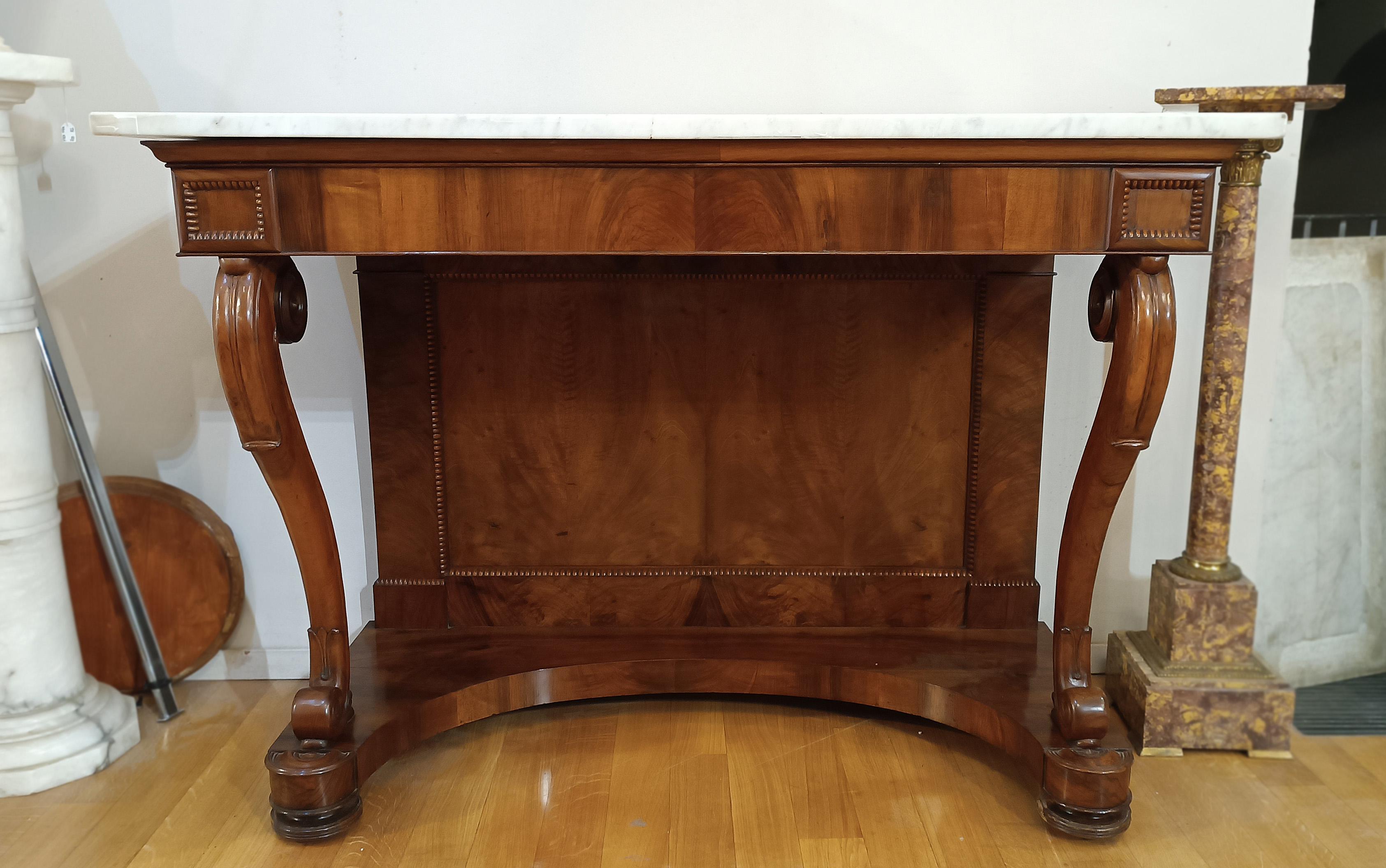 Beautiful console table belonging to the Charles X period. The piece of furniture was made of solid walnut, finished with walnut veneer and features an elegant white Carrara marble top. The shelf legs are finely finished in a curl, adding a touch of