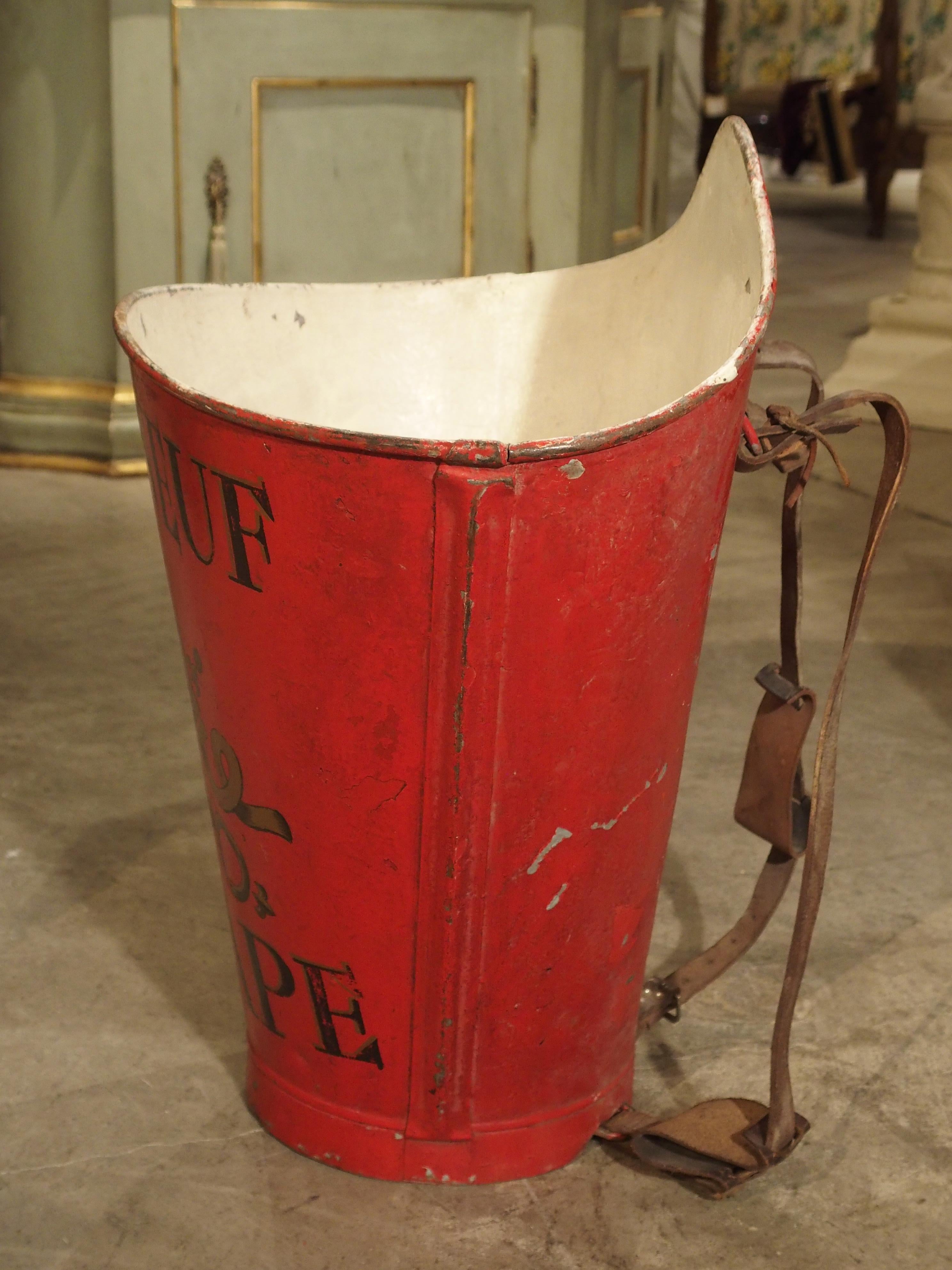 This colorful French metal container is known as an hotte. They were used for grape collecting in vineyards all over France during the 19th and early 20th centuries. This hotte has been painted with Chateauneuf du Pape and has an ornate central