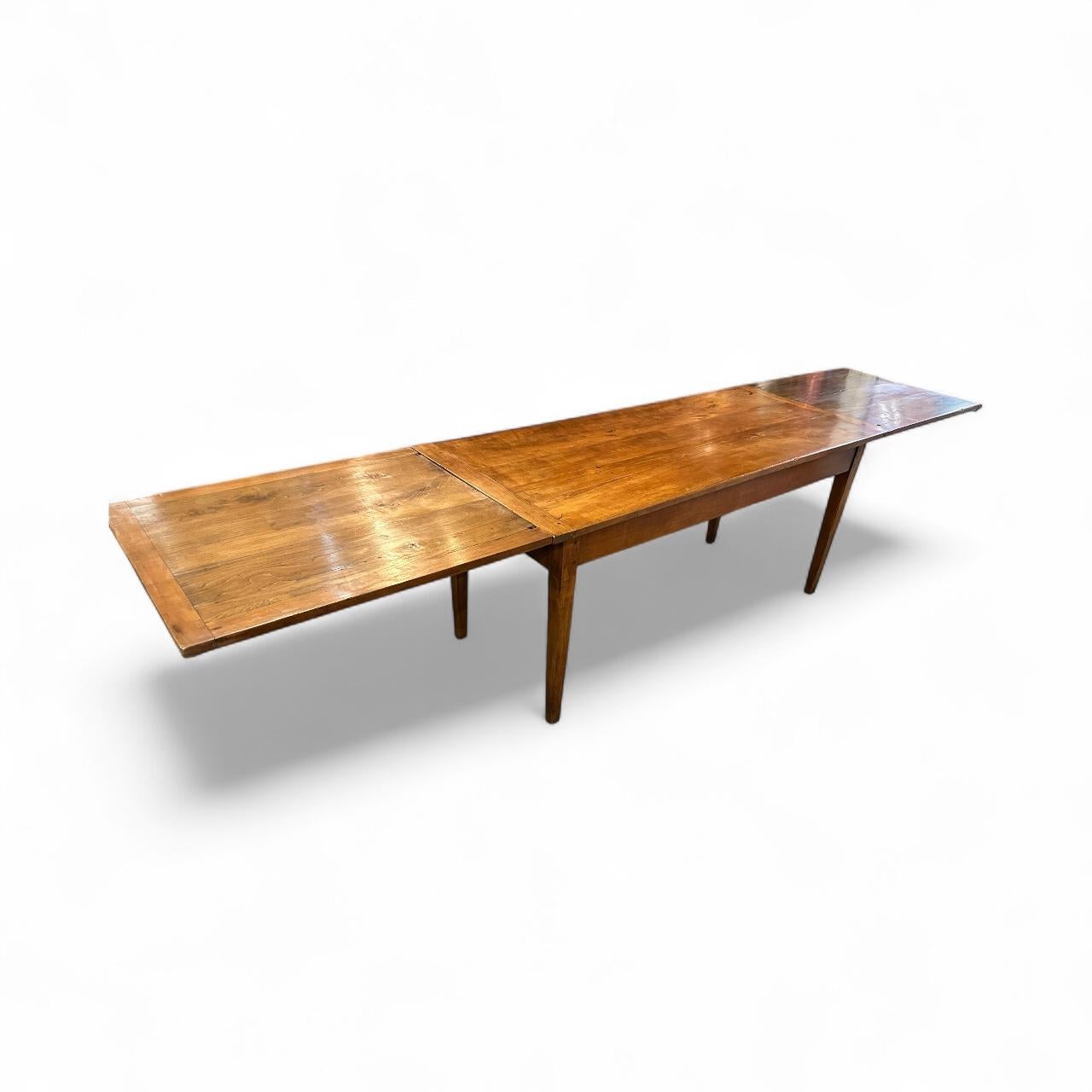 Table de salle à manger à double rallonge en cerisier du 19e siècle, d'une belle couleur et d'une riche patine. La table repose sur un élégant piètement aux pieds fuselés, offrant un espace généreux pour les jambes. Lorsqu'il est fermé, il accueille