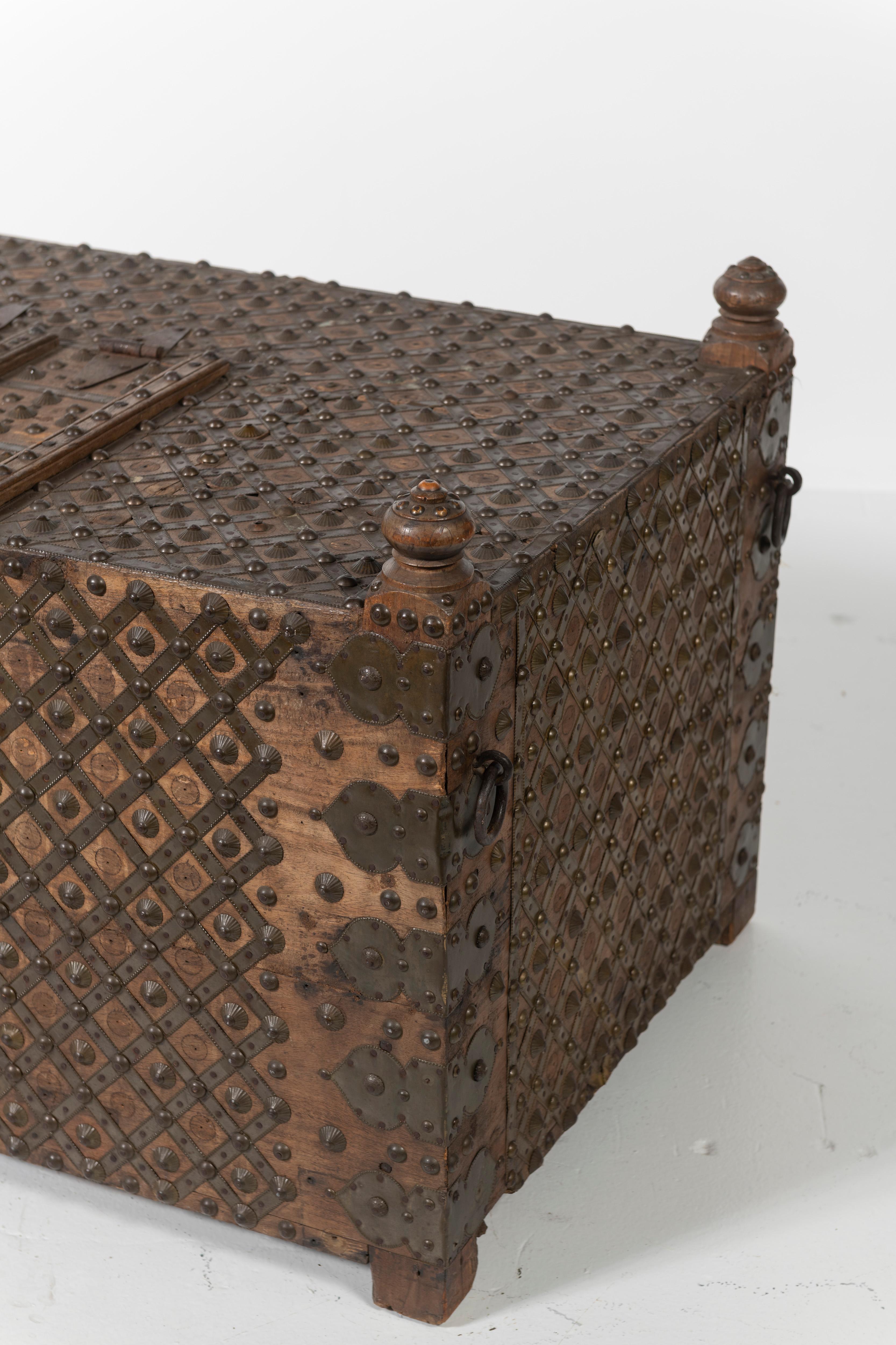 Of Indian origin, this beautiful teak trunk is wrapped in iron and studded with brass accents in an intricate yet simple pattern. Fully functional for storage or use as a coffee or cocktail table, the piece is in very good condition.
