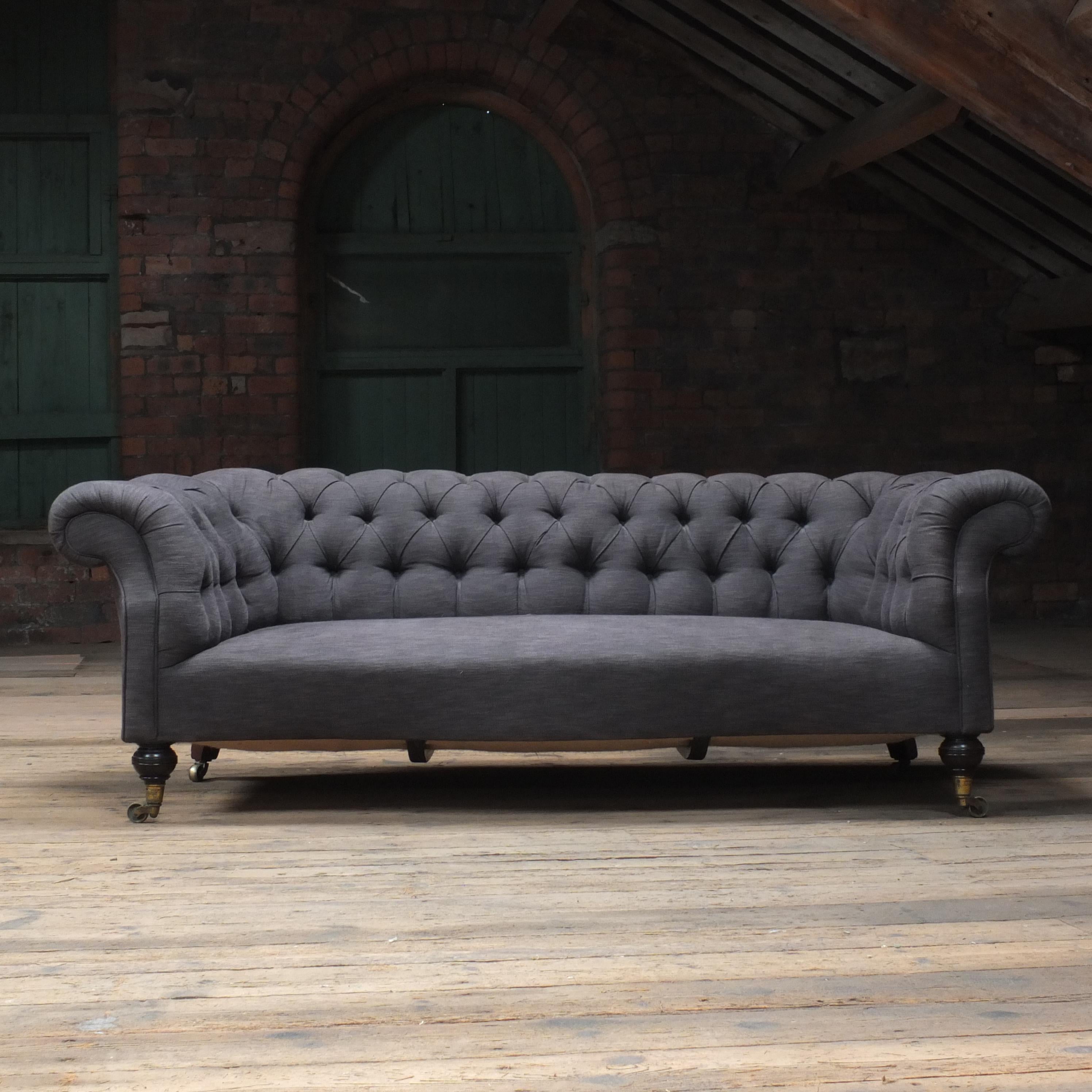 A Large country house English chesterfield sofa by Howard & sons - London. Raised on Howard's uniquely ring turned walnut legs to the front and out swept to the back. Both front castors by cope and Collinson, one back castor has unfortunately been