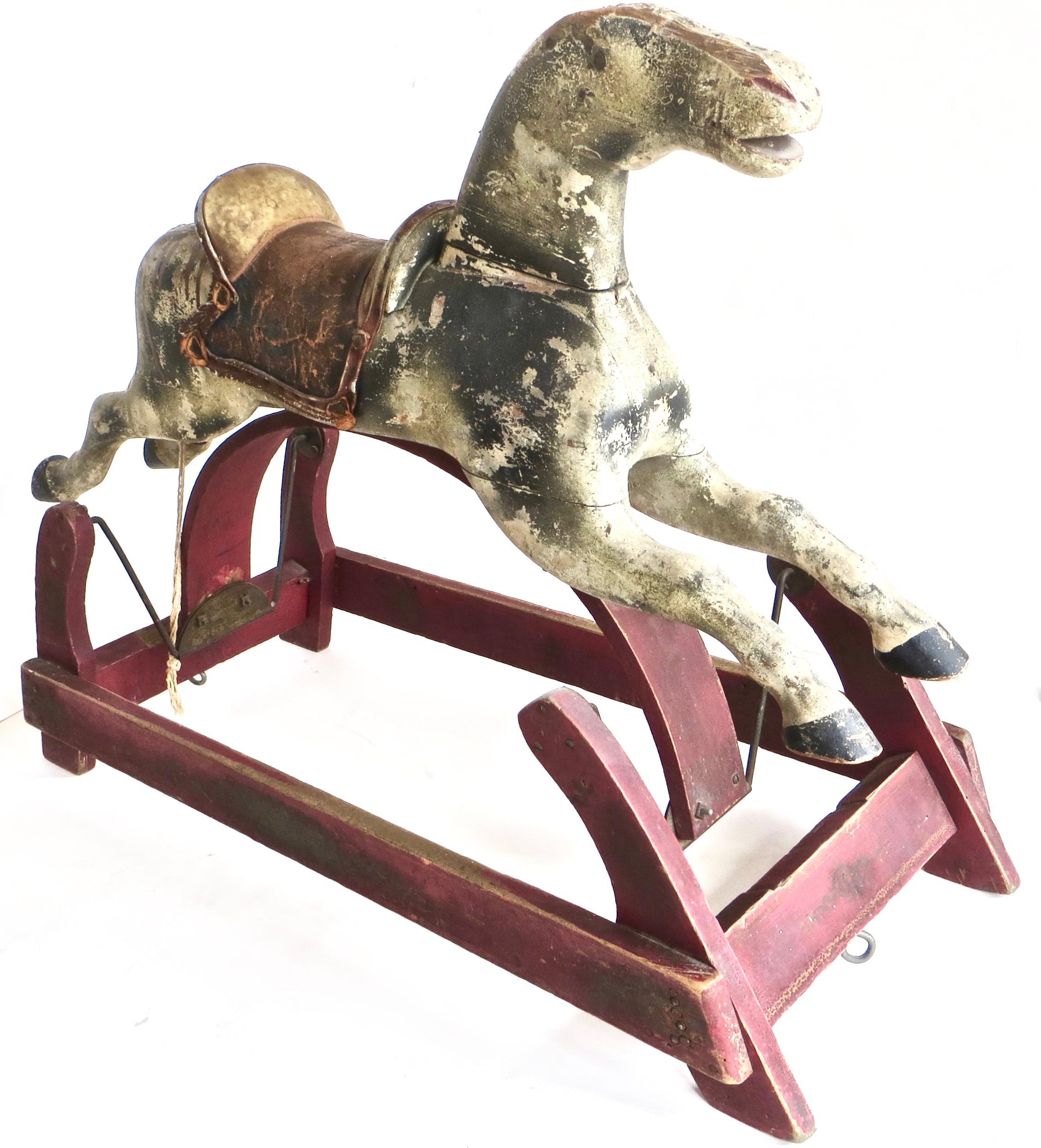 De fabrication américaine, vers 1875, cet authentique cheval à bascule pour enfants est sculpté à la main dans du bois dur et possède une selle en cuir fabriquée à la main. L'enfant assis peut se balancer d'avant en arrière lorsqu'une autre personne