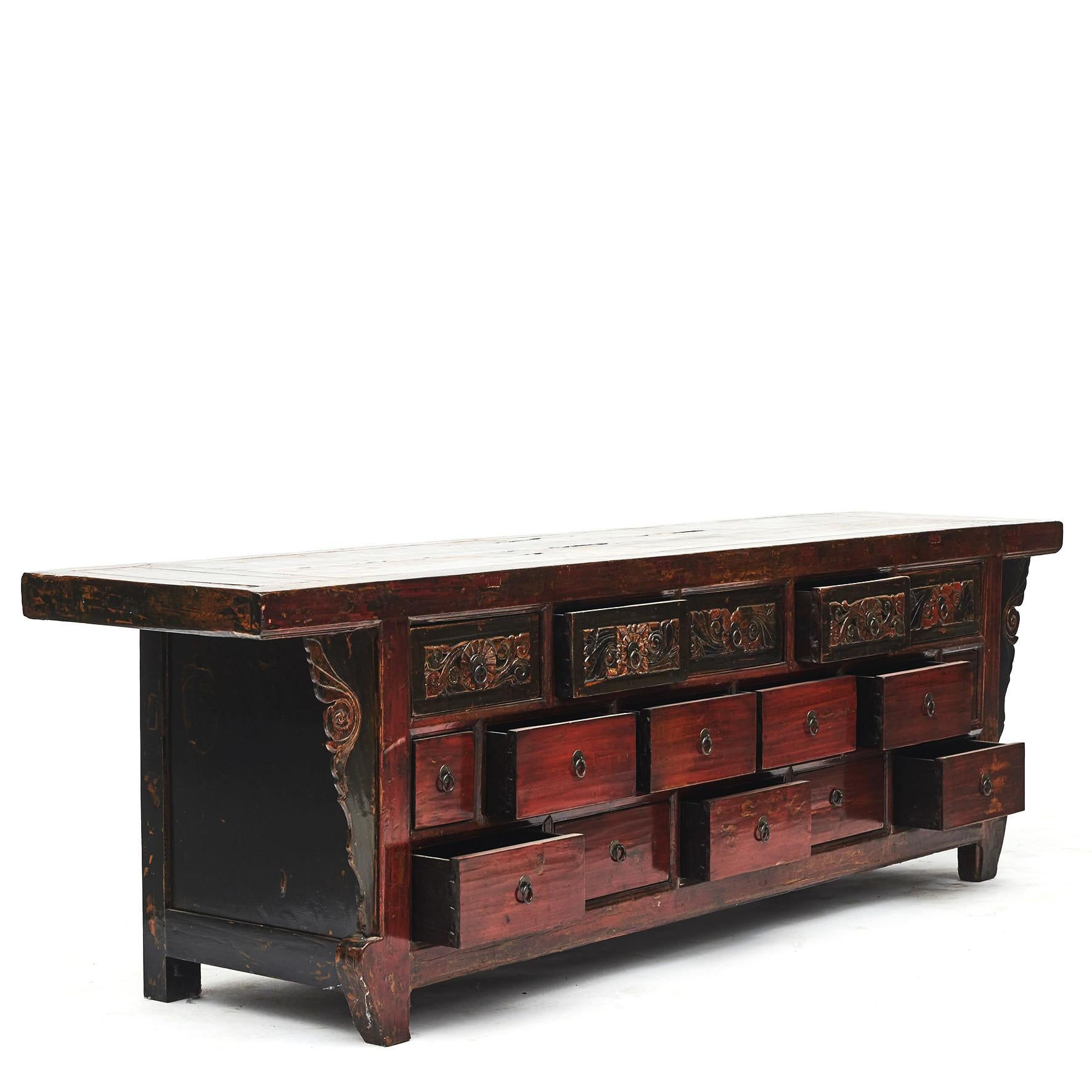 This large 19th century Chinese elmwood altar sideboard features a rectangular top sitting above 16 drawers flanked by two carved spandrels connecting the front to the cabinet's top.
Original lacquer in black, red and green colors.
Top drawers and