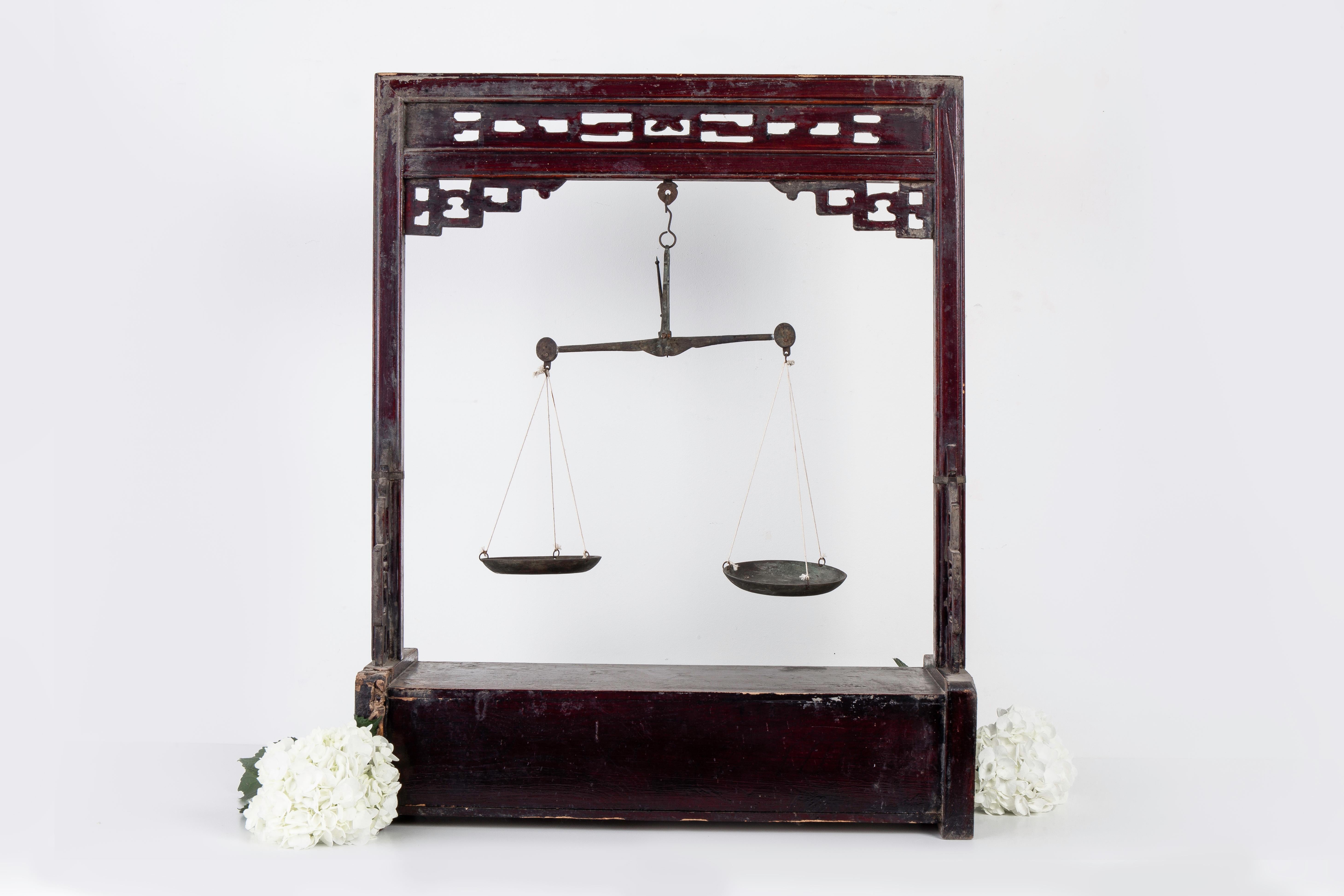 Large Chinese carved wood apothecary balance scale with stand and storage drawer cabinet. It features beautiful carved fretwork on the top and sides featuring brass metal hardware and trim. It is finished in its original dark red lacquer which has