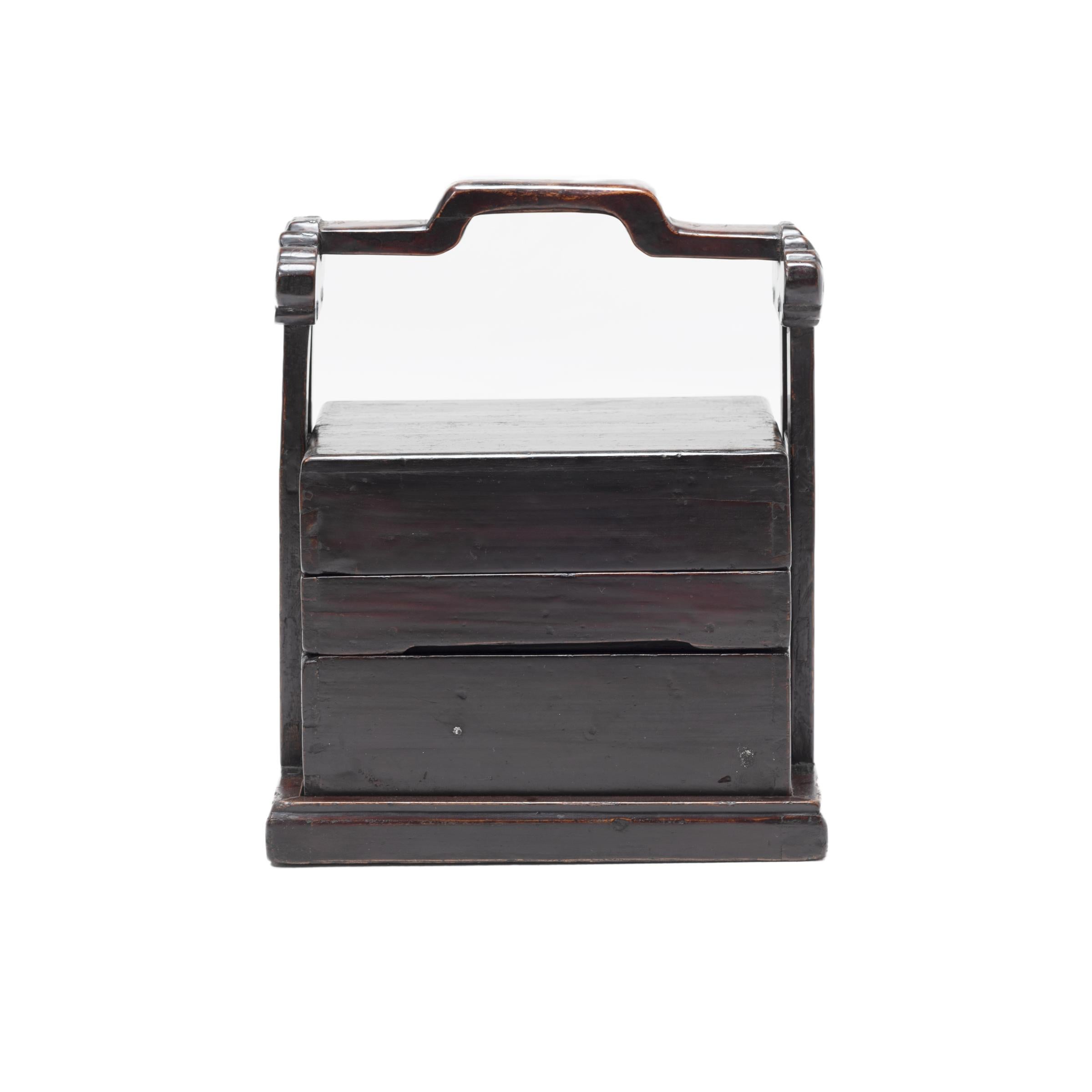 The basic form of this three-tiered rosewood box with handle has remained unchanged for a thousand years. The lack of formal dining rooms in traditional China prompted families to use stacked boxes to carry food from a remote kitchen to the room
