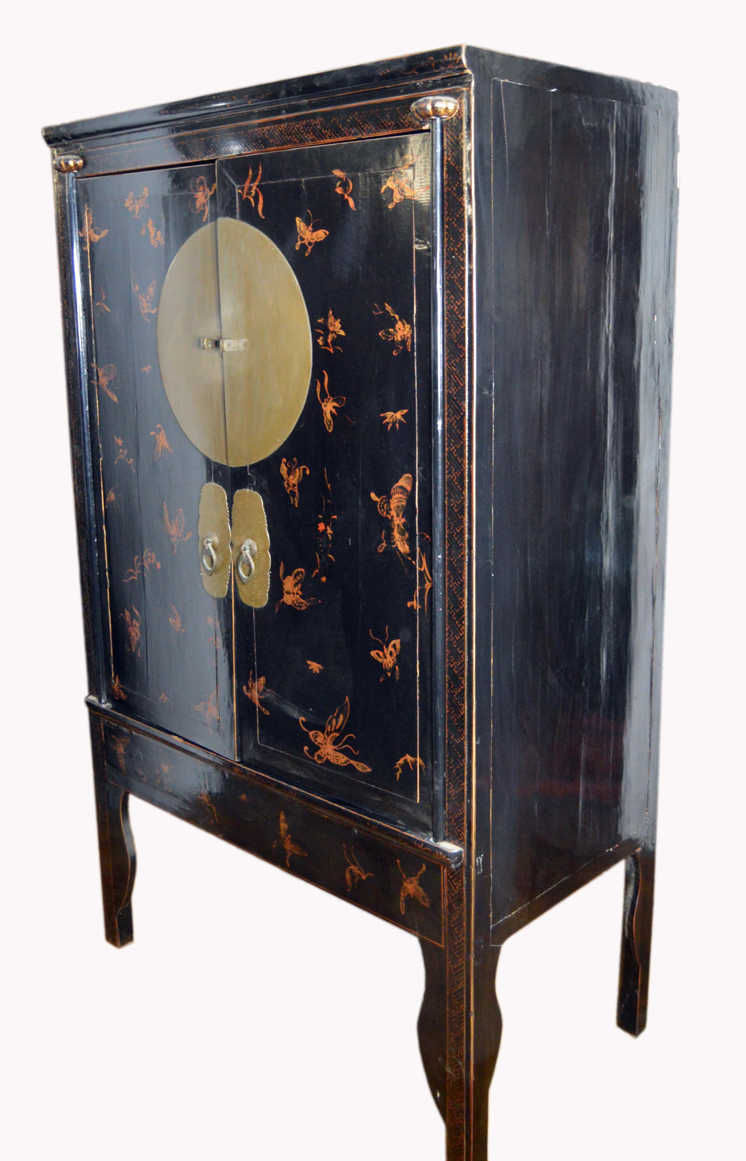 A Chinese 19th century wedding cabinet made with black lacquered wood and gilt painting. This armoire adopts a rectangular shape raised on undulating bracket feet in the front and simple straight legs in the back. The front legs are supported by a