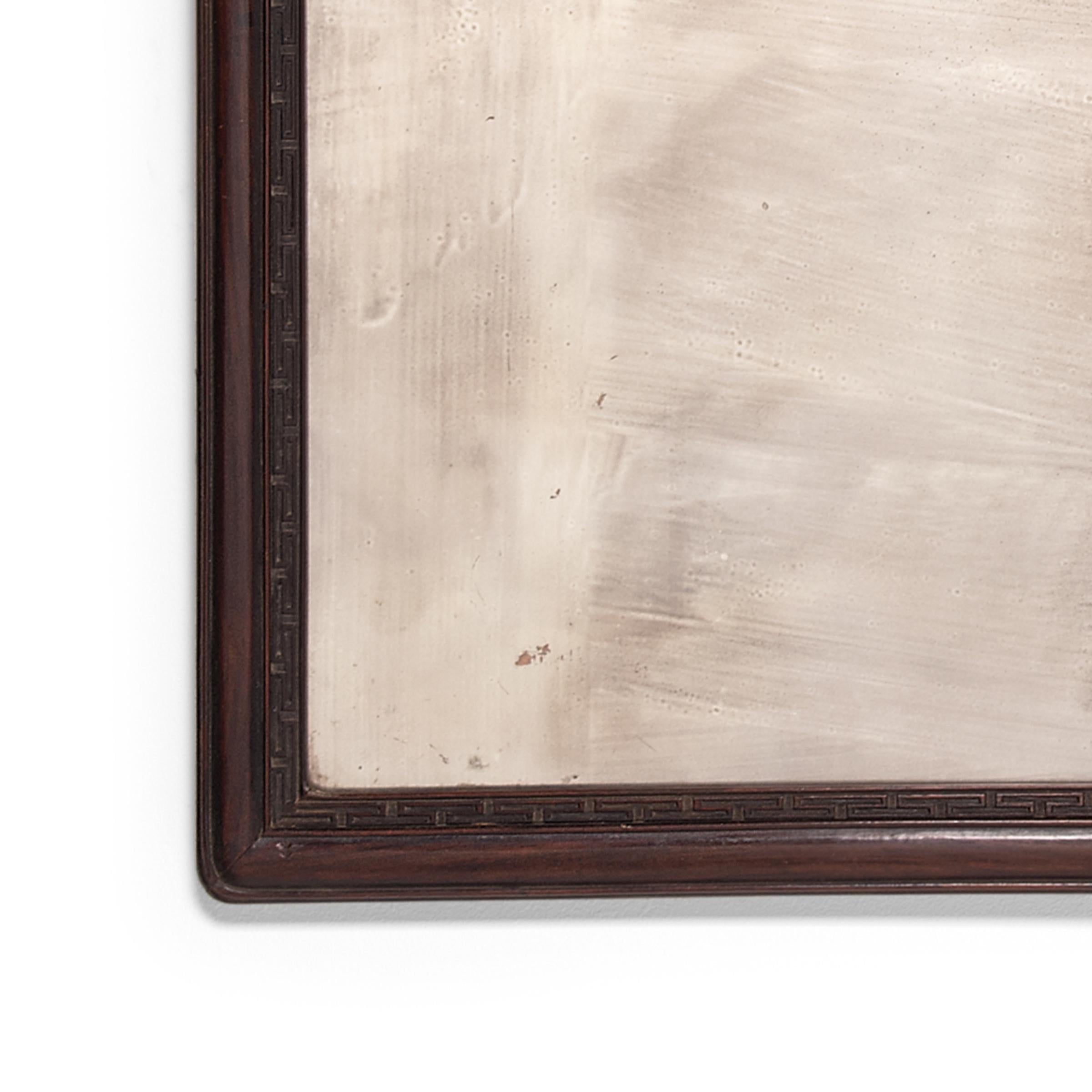 Often featured in heavily carved furniture, fine blackwood forms a simple frame of dark wood in this 19th-century mirror. Detailed only with subtle meander molding and rounded corners, the dark, fine grain wood beautifully contrasts with the silvery