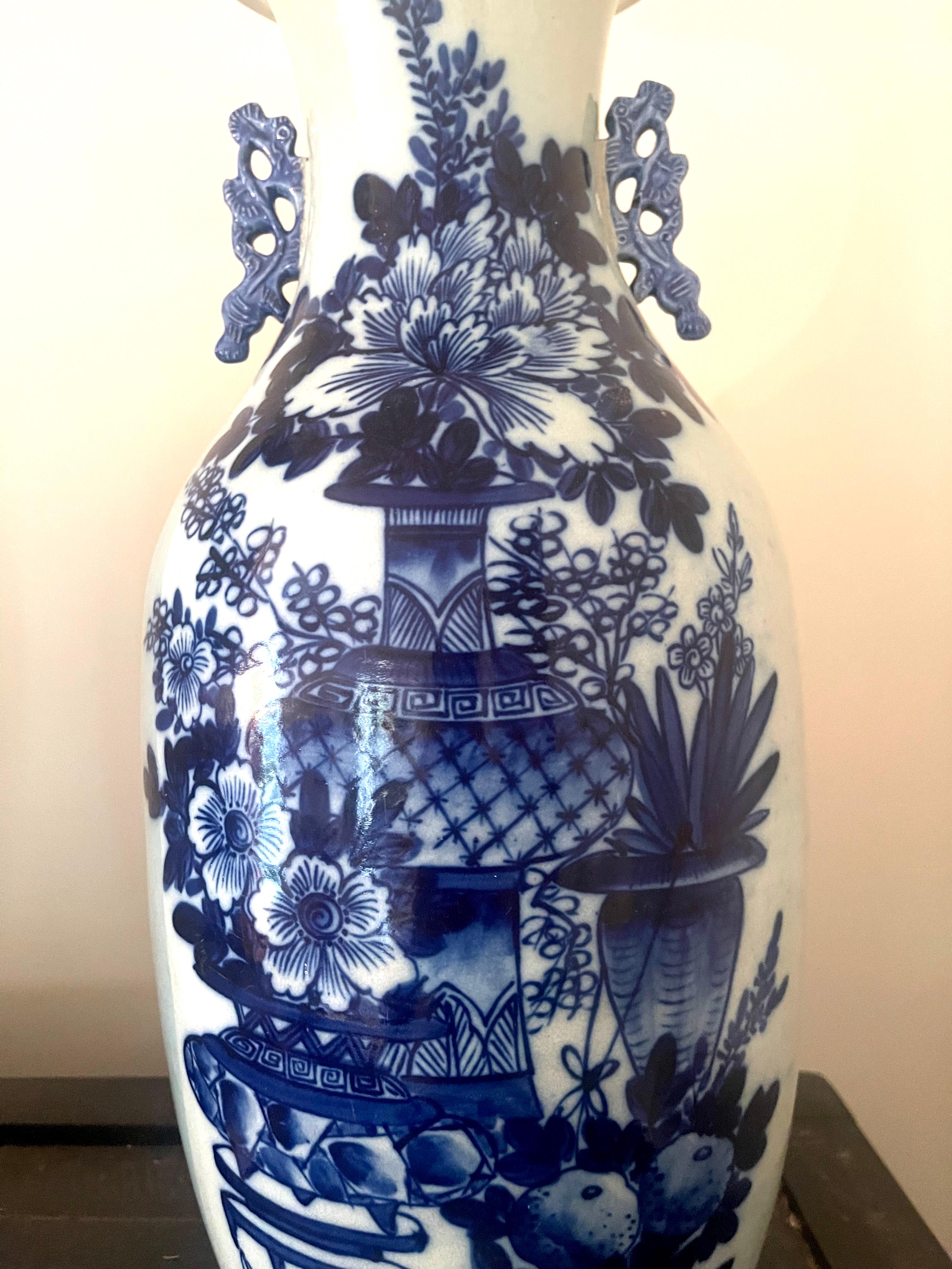 A fine antique 19th century Chinese porcelain large baluster vase decorated with various flowers and objects in low relief and underglaze cobalt blue within a white-glazed ground. The vase has molded stylized handles in cobalt blue to either side of
