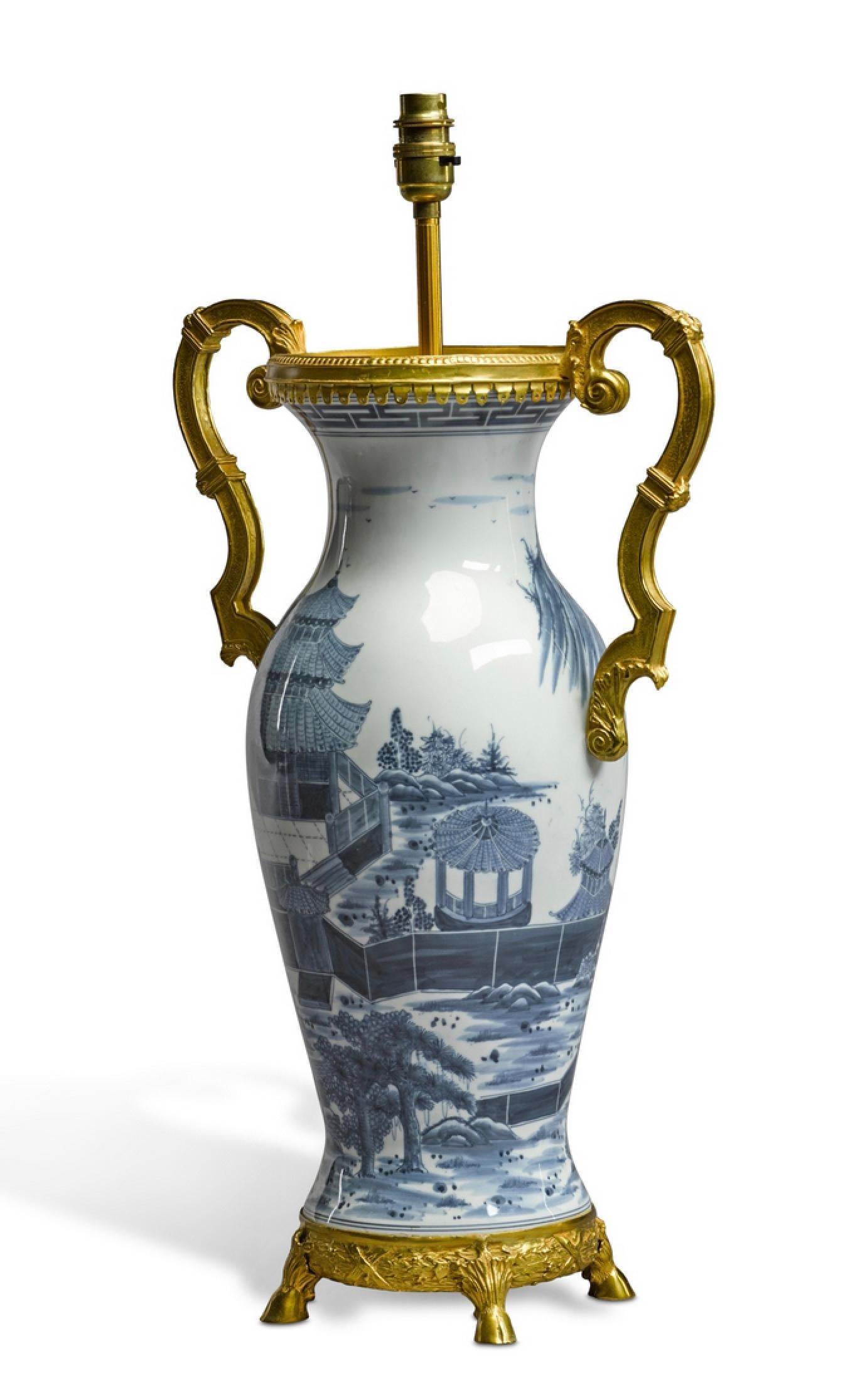 A superb Chinese blue and white porcelain baluster vase embellished with fine ormolu mounts including winged handles.
The vase decorated in tones of blue on white depictig a village scene with houses, pavilions and trees. Now mounted as a