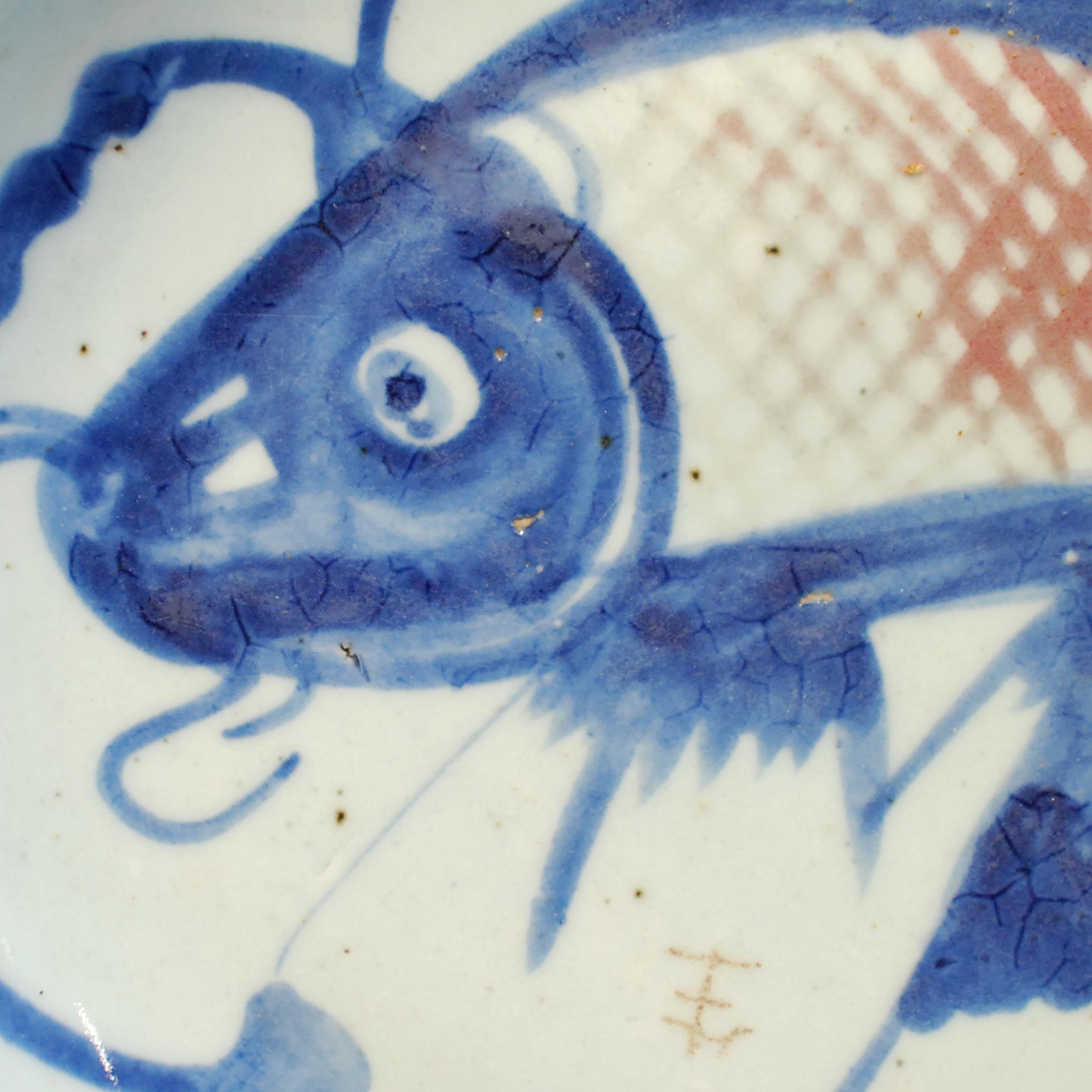 The fish on this hand painted 19th century provincial plate represents a blessing for wealth. Chinese symbols take on added meaning and nuance when combined with other motifs. The blue lines around the fish suggest water, which together would offer