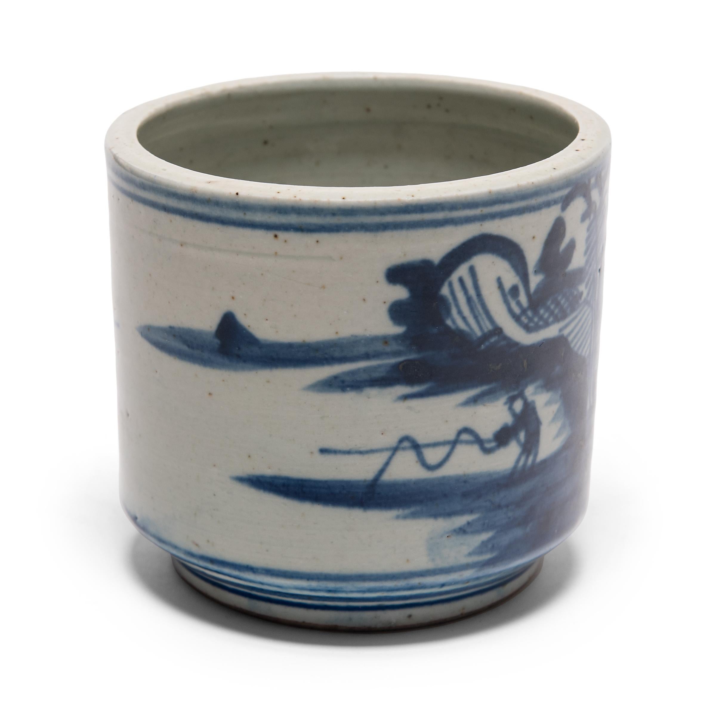 This blue-and-white porcelain brush pot would have been right at home in a Qing-dynasty scholar’s studio. Brushed with a rich cobalt blue glaze, the pot is expressively painted with a serene landscape, featuring a small house and fisherman mid-cast.