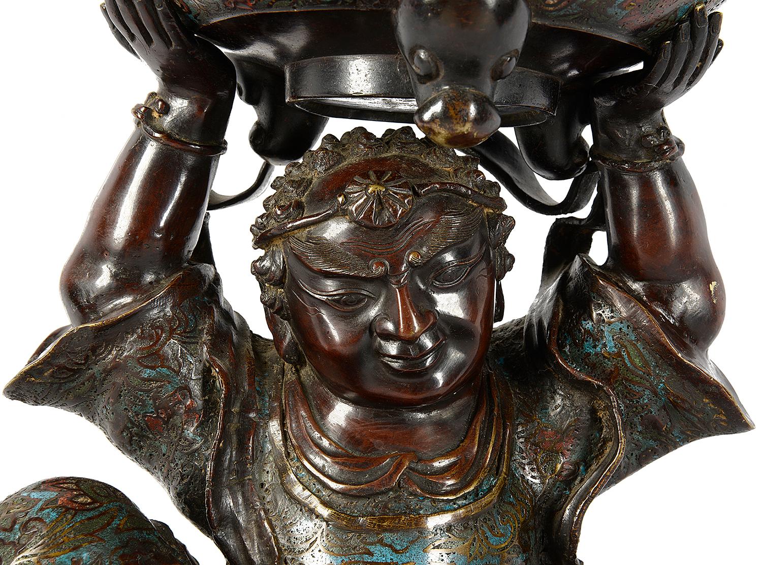 A good quality turn of the century Japanese bronze, enameled, seated figure of a man holding an incense burner above his head.