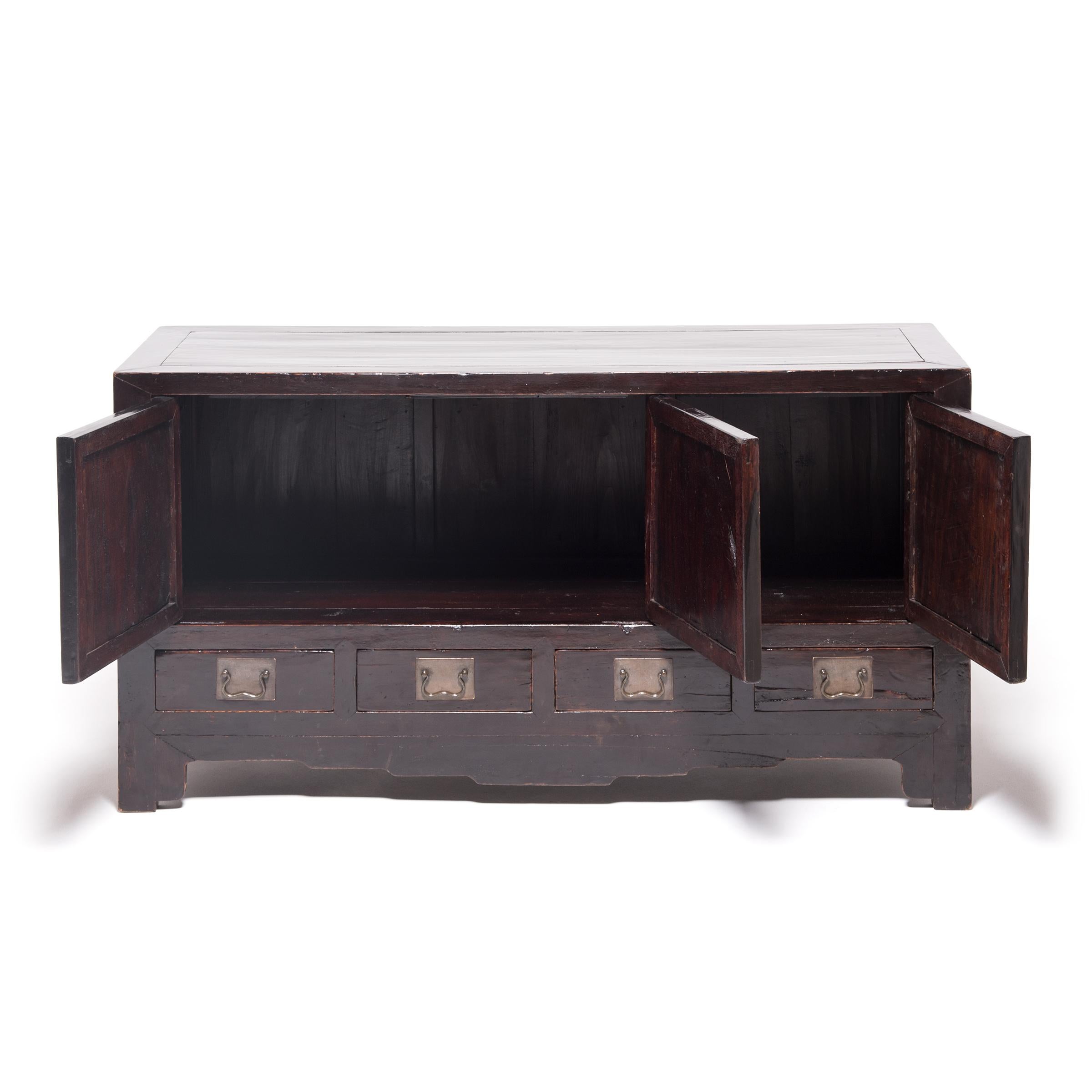 Intricately crafted in the 19th century, this walnut kang chest showcases three doors inset with camphor panels, reminiscent of cartouche paintings. Often selected for its active grain and hardy nature, camphor wood was a popular choice during the