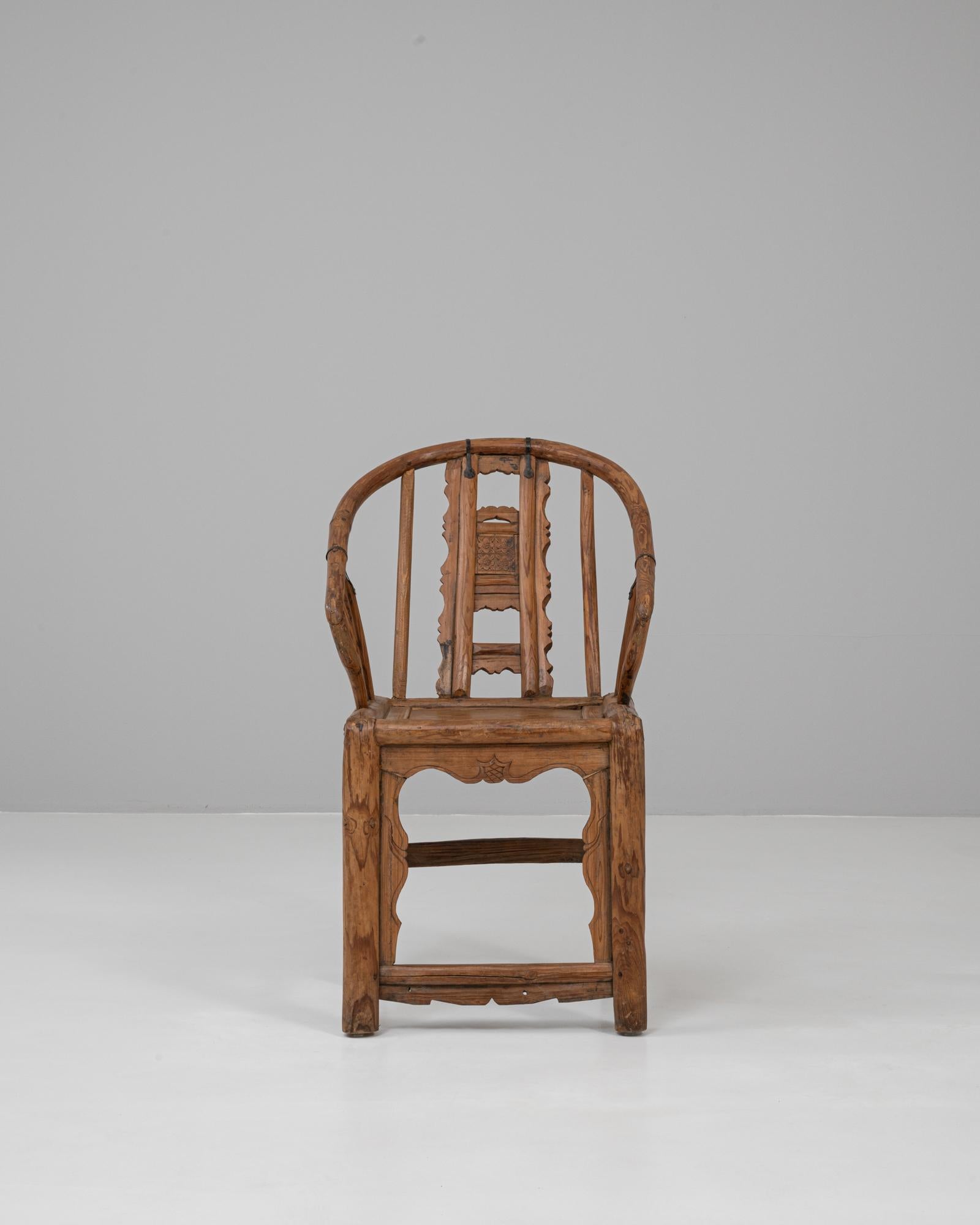 Questa poltrona cinese in legno di bengala intagliato del XIX secolo esemplifica l'artigianato tradizionale e il design elegante, fondendo funzionalità e arte. Realizzata in legno con una ricca venatura, la sedia presenta uno schienale continuo e