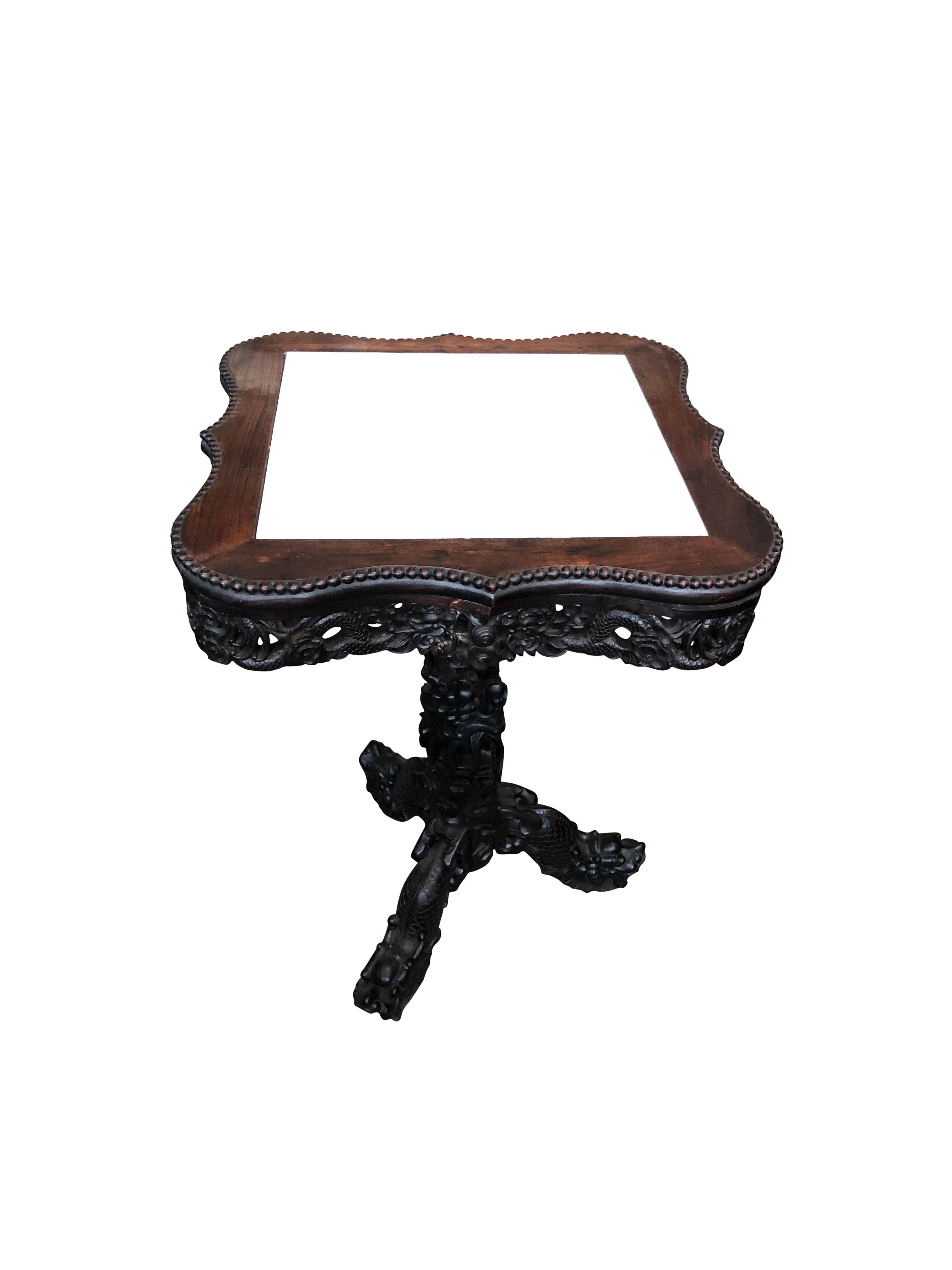 A square 19th century Chinese carved hardwood center table with marble top. Inset white marble top with decorative base. Standing on 3 carved legs that slot into the base. The stand is carved into the body of a twisting dragon. Spectacular carving