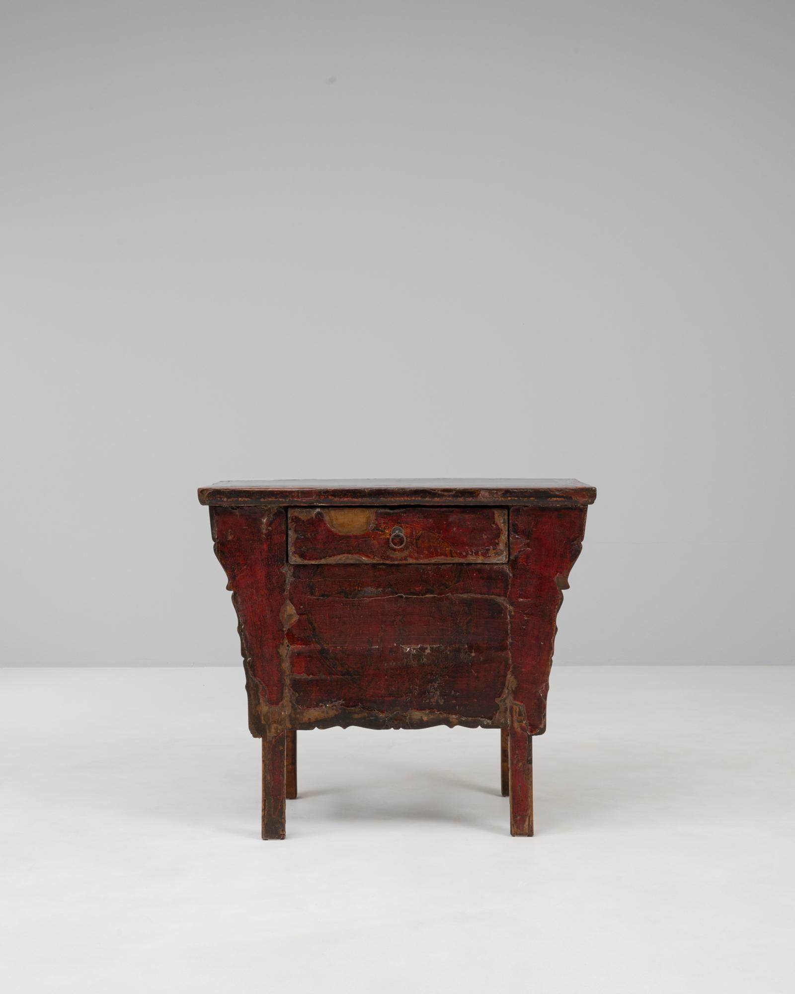 Cette table console chinoise du XIXe siècle présente une étonnante finition laquée rouge, adoucie par le temps et l'usure qui soulignent sa riche histoire. Le tiroir unique est subtilement intégré au tablier sculpté à la main, orné d'une silhouette