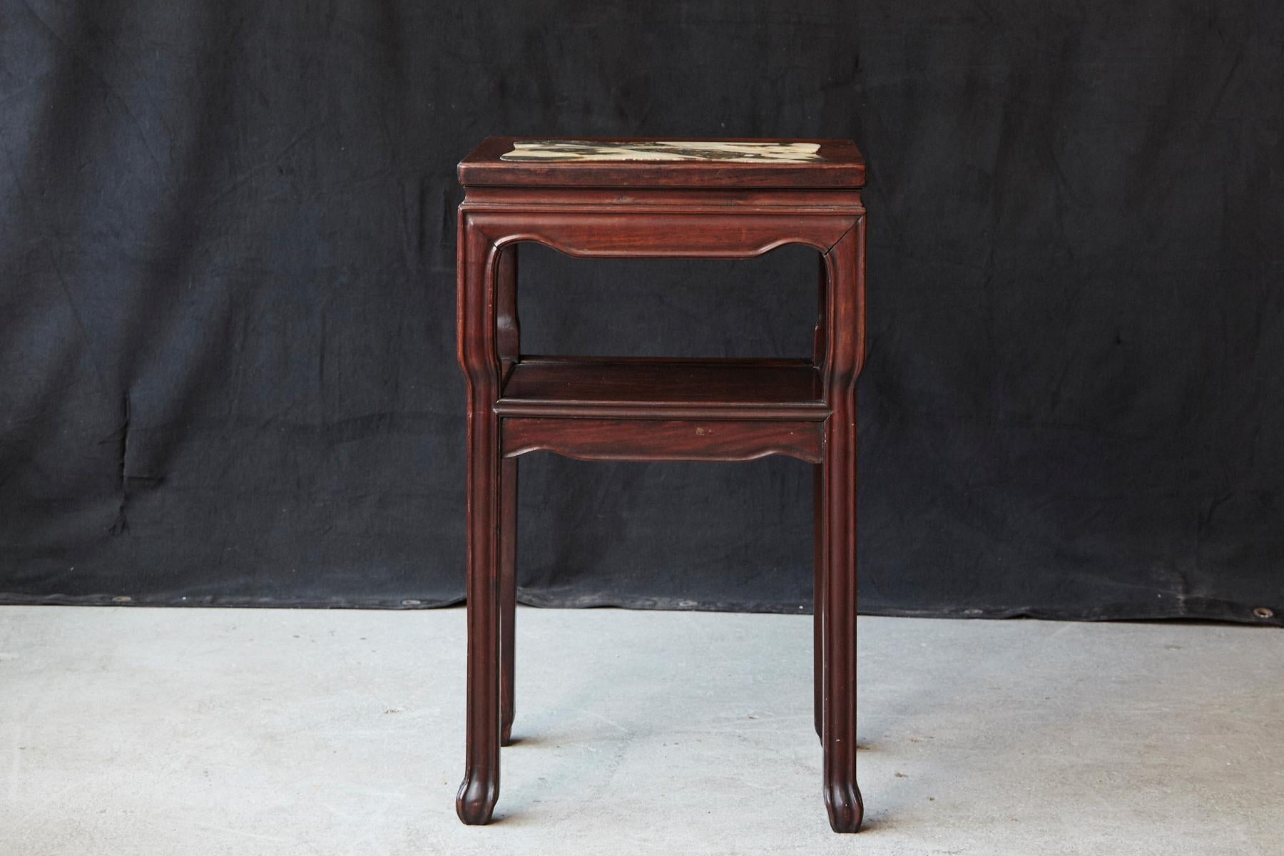 Early 20th century Chinese rectangular hardwood table with minimalistic molded carvings on the panels and legs, rectangular marble inset with rounded corners, one shelf and square legs ending in symbolic claw feet.
There are some minor flaws to the