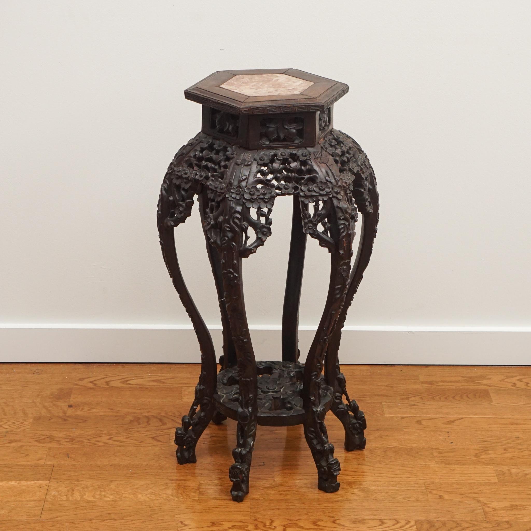 The exquisitely carved rosewood plant stand, shown here, reflects the character of its age and intricate detailing. Made in China in the mid 19th century, the plant stand features an octagonal inset marble top. The shape, scale, and vintage patina
