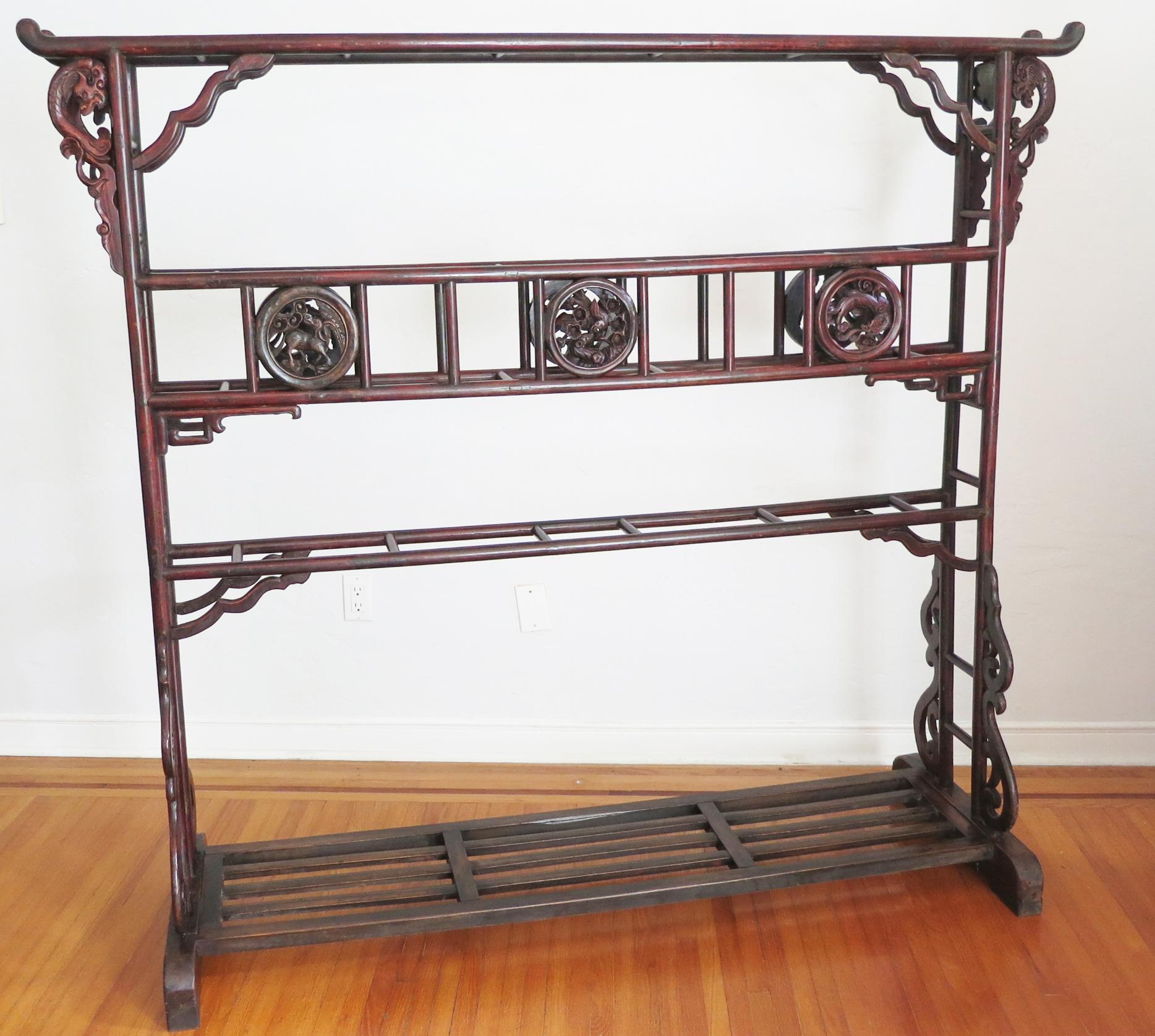 This large Chinese oxblood colored lacquered robe rack is carved from Northern Elm (yumu) and is from the Shanxi Province of China. These robe racks were design to drape the ornate silk robes over the top of the racks and typically they were kept in