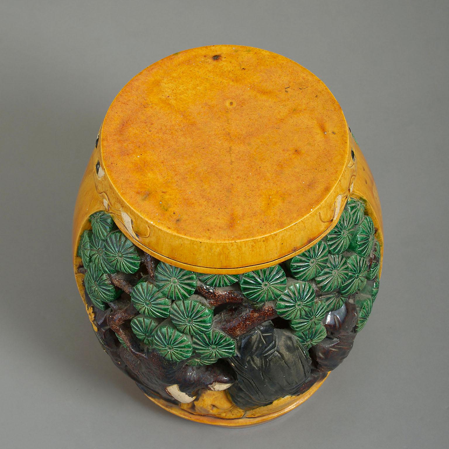 A 19h century Chinese ceramic garden seat or low table of barrel-form, boldly modelled and pierced with a big cat surrounded by prunus trees.