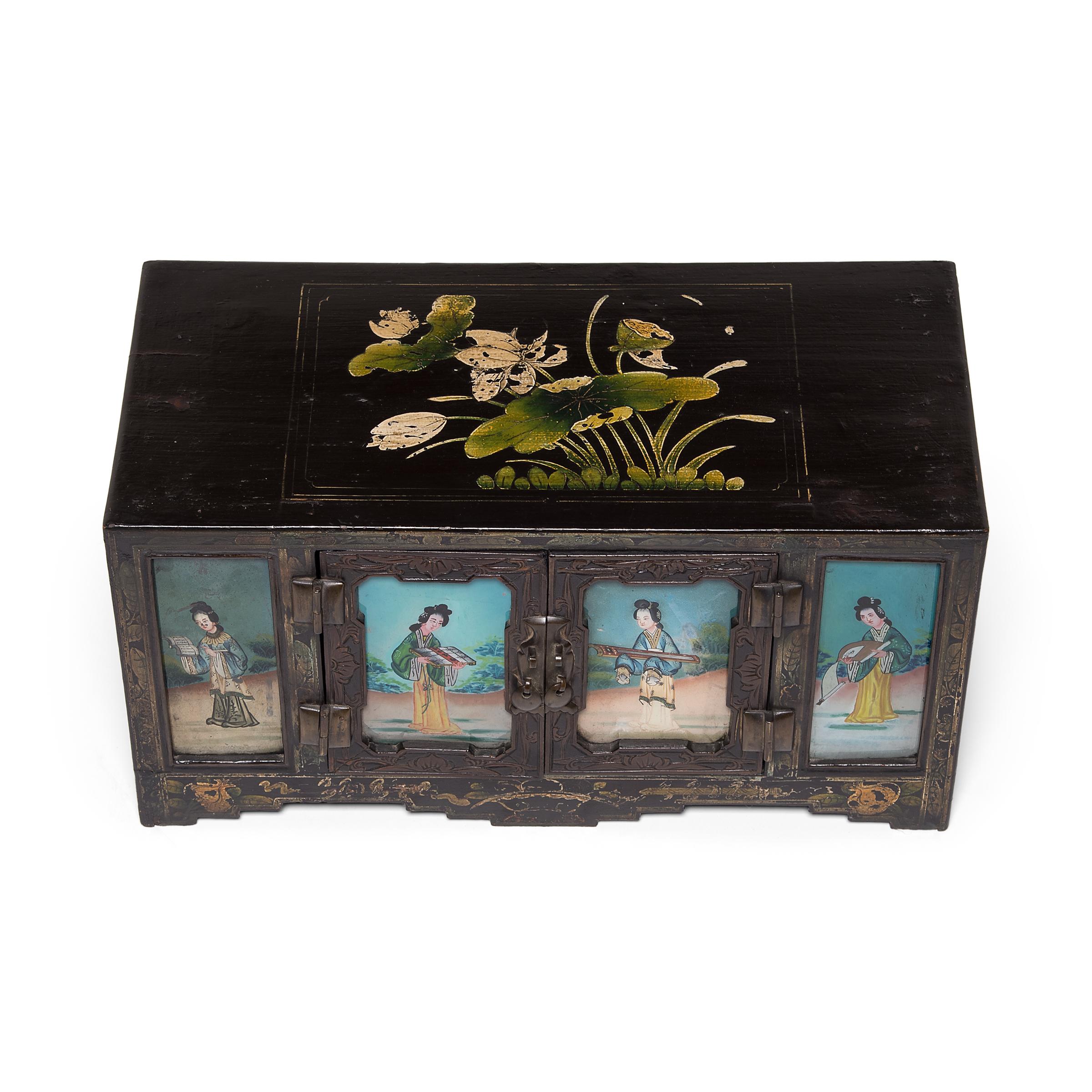As much an artwork as a piece of furniture, this 19th century treasure chest from northern China is richly decorated with relief carvings and delicate gilt paintings. The doors bear inset reverse glass panels painted with beautiful women, the apron