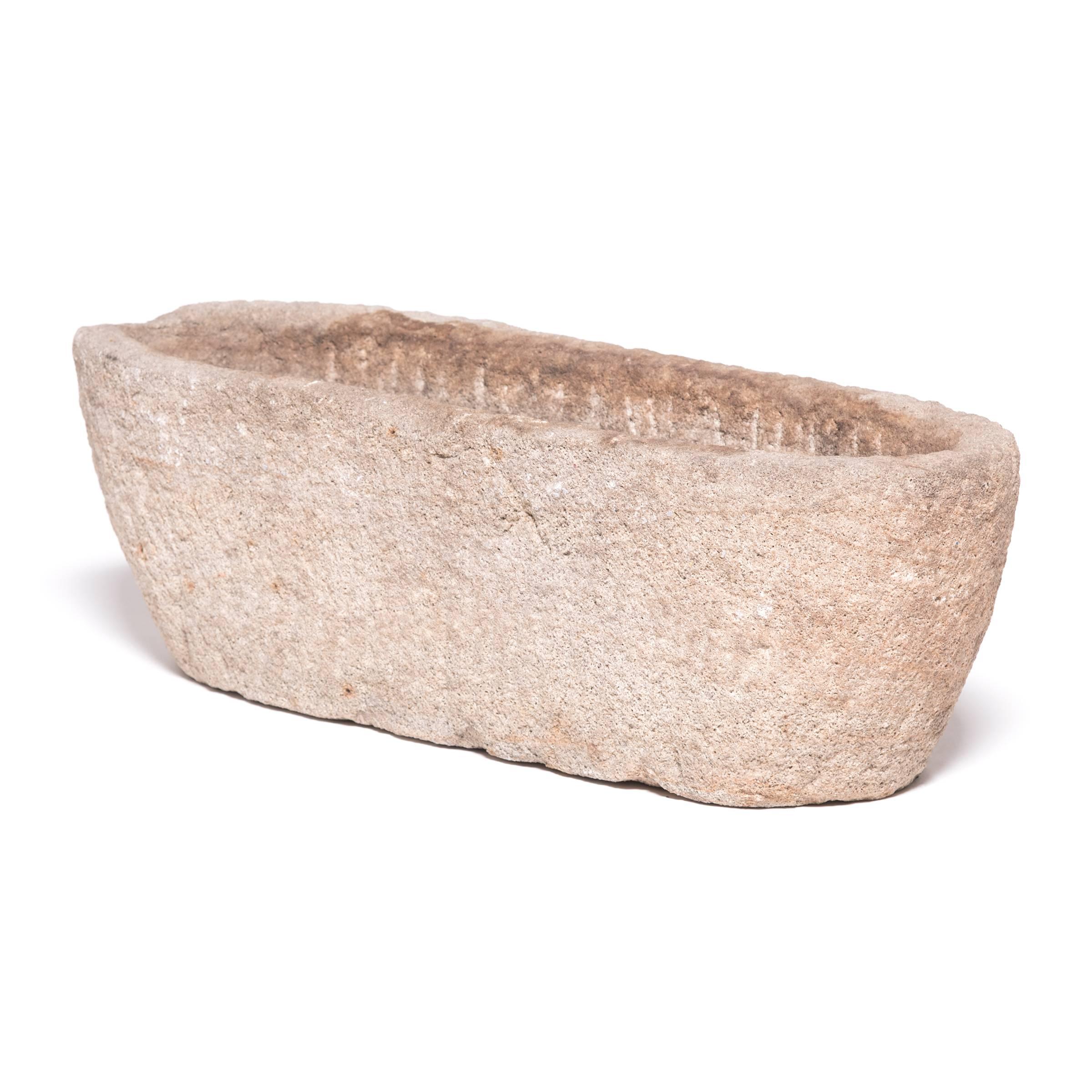 Once a common sight in courtyards throughout rural China, this textured stone trough was filled with grain for chickens and other barnyard fowl. Chiseled from a block of stone over a century ago, the deeply weathered vessel has endless stories to