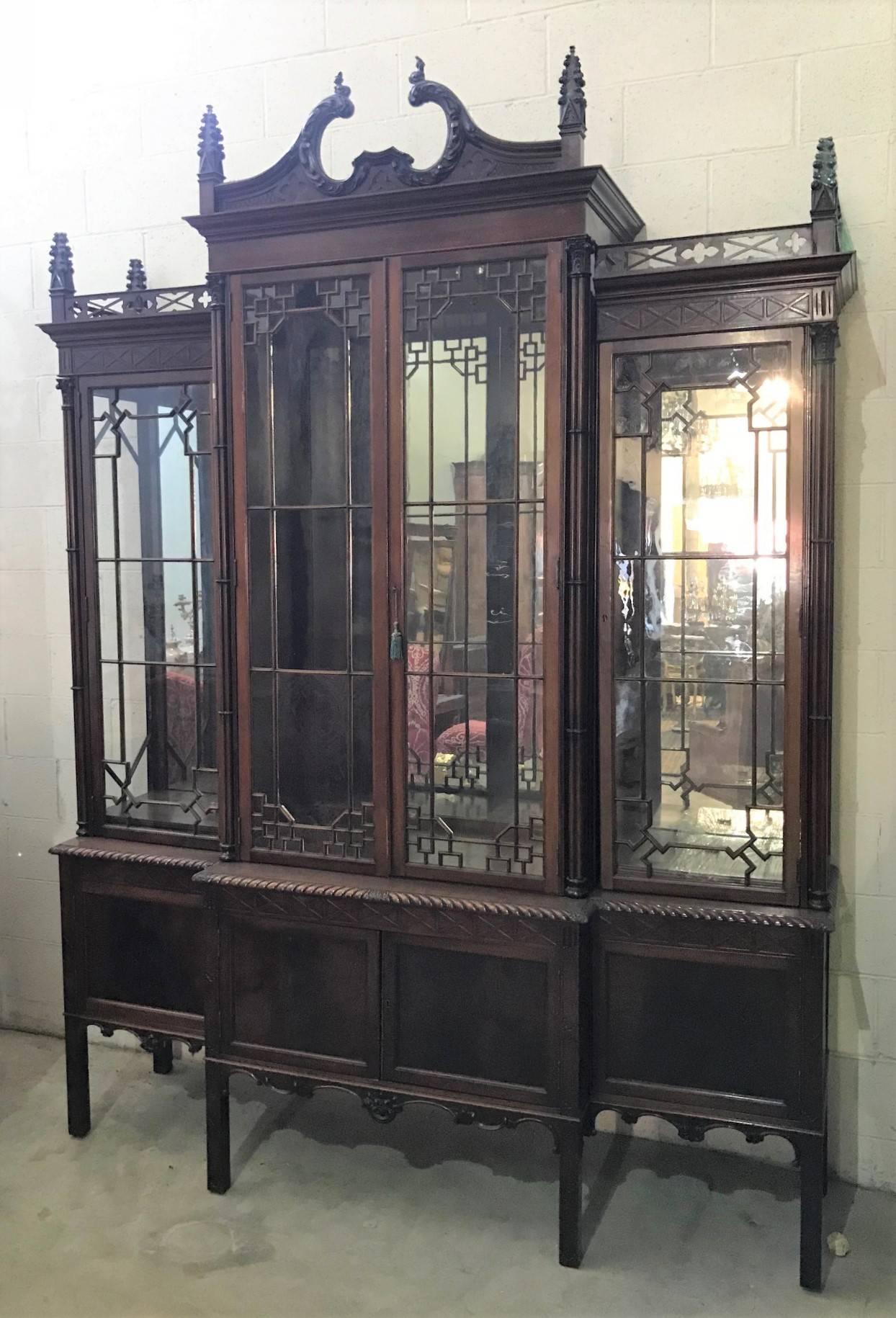 Magnificent 19th century Chinese Chippendale mahogany breakfront bookcase having a superbly carved swan's neck pediment with carved steeple finials, pierced gallery and blind fret frieze. 

The large glazed pane door with intricate astragal