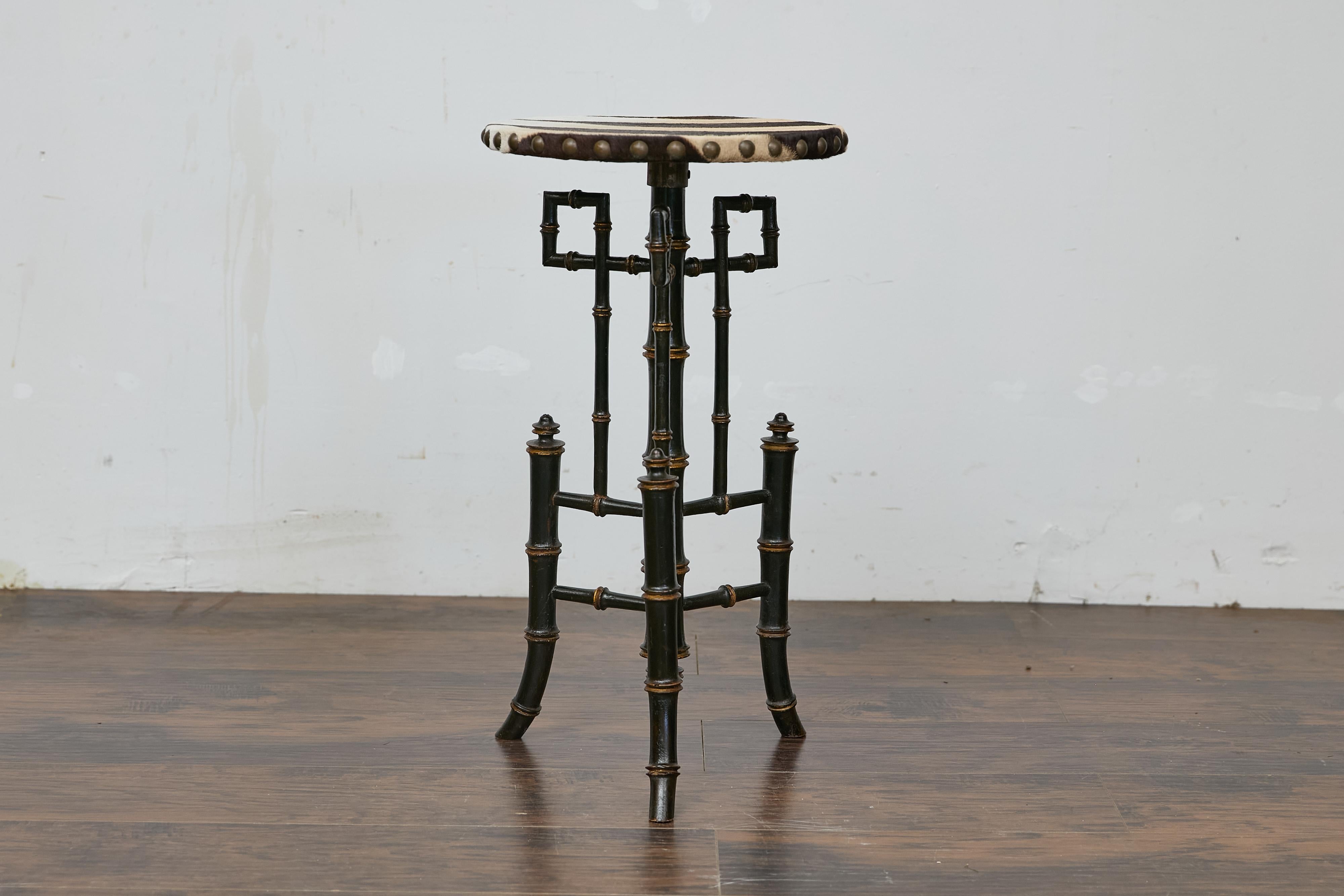 An English Chinese Chippendale side table from the 19th century with ebonized faux bamboo base and zebra hide round top. This 19th-century English Chinese Chippendale side table features an ebonized faux bamboo base, exemplifying the fascination