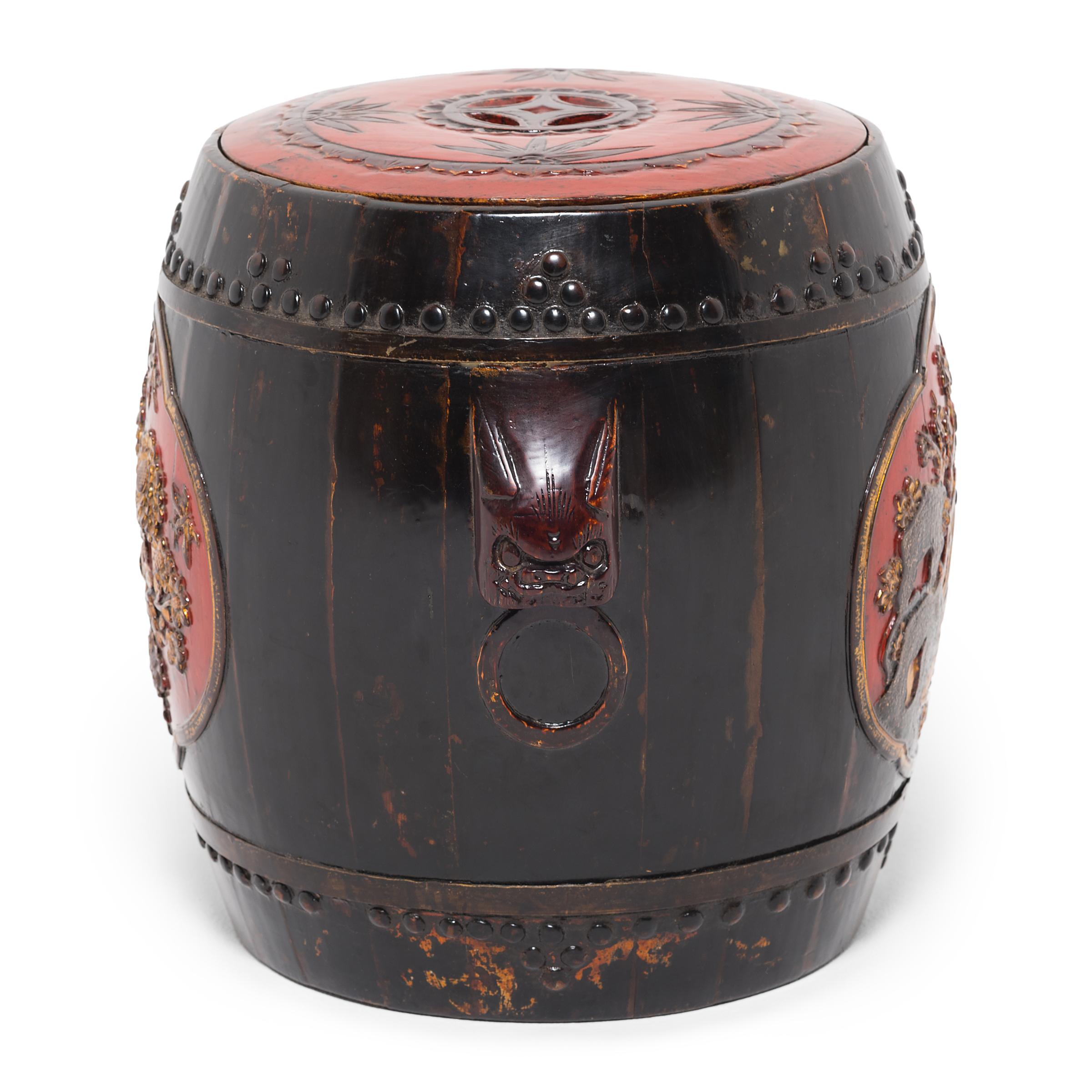 This 19th century drum-form stool is assembled with traditional stave and hoop construction, with two bands of decorative nailheads. Painted in red and gold, two colors thought to bring good luck, the stool is adorned with low-relief carvings of