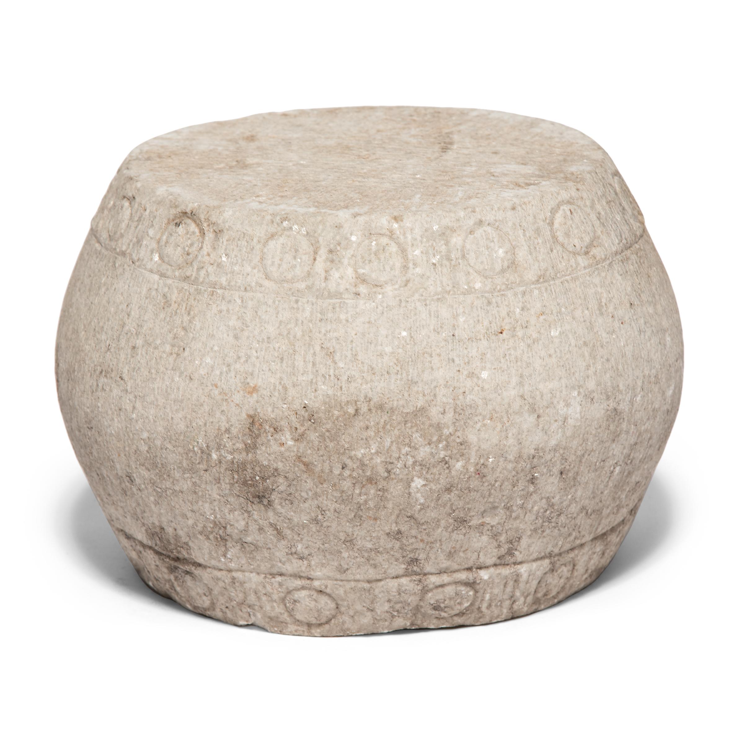 This drum form pedestal was carved from a single block of white marble by Qing dynasty artisans in the mid-19th century. Ringing both its top and bottom, an etched pattern of nailheads imitates those used to stretch a skin on an actual drum. At the