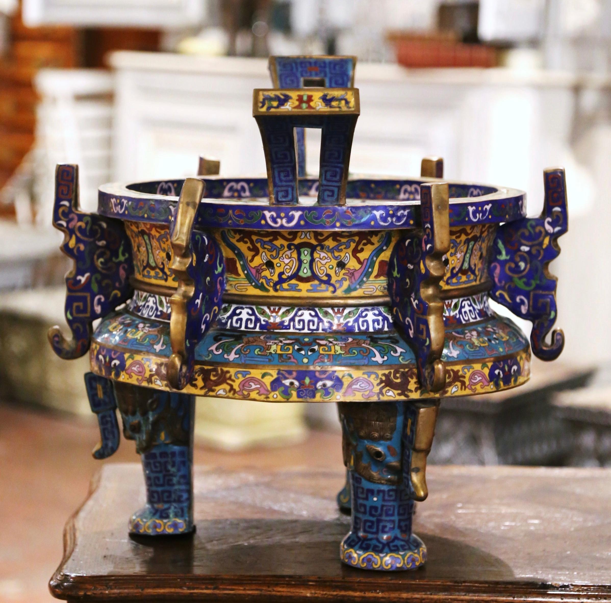 This colorful antique champlevé “planterette”, or cache pot, was crafted in China circa 1870 and features ornate and intricate cloisonne decor with vibrant and bold colors throughout the pot. Supporting the flowerpot are three elephants displaying