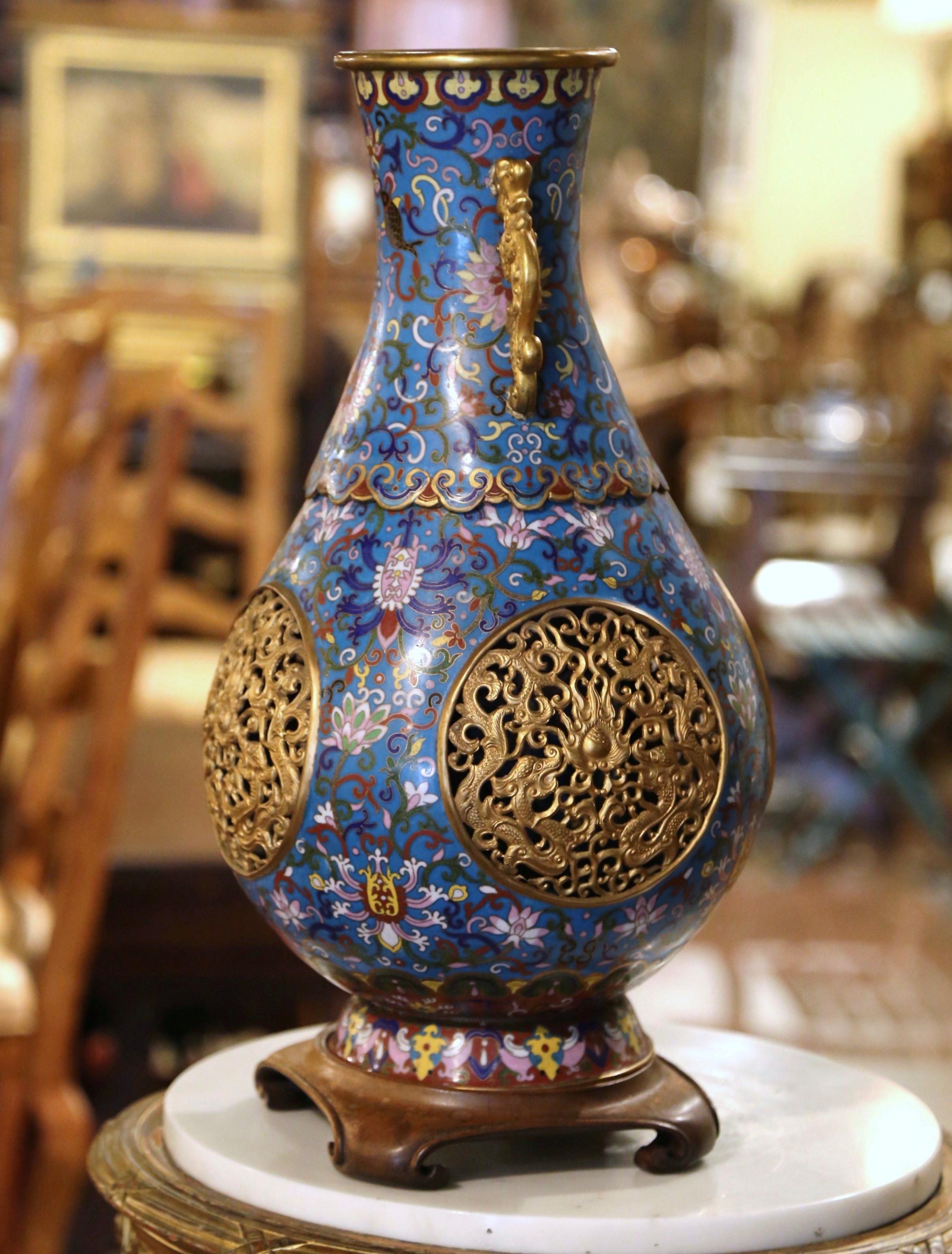 Dekorieren Sie einen Tisch oder ein Buffet mit dieser eleganten und farbenfrohen antiken Vase. Das um 1880 in China gefertigte Gefäß steht auf einem vierbeinigen Holzsockel mit geschwungenen Füßen; es hat einen Emaille-Körper in der traditionellen